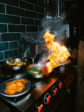 Chef flambeing food in a pan on stove