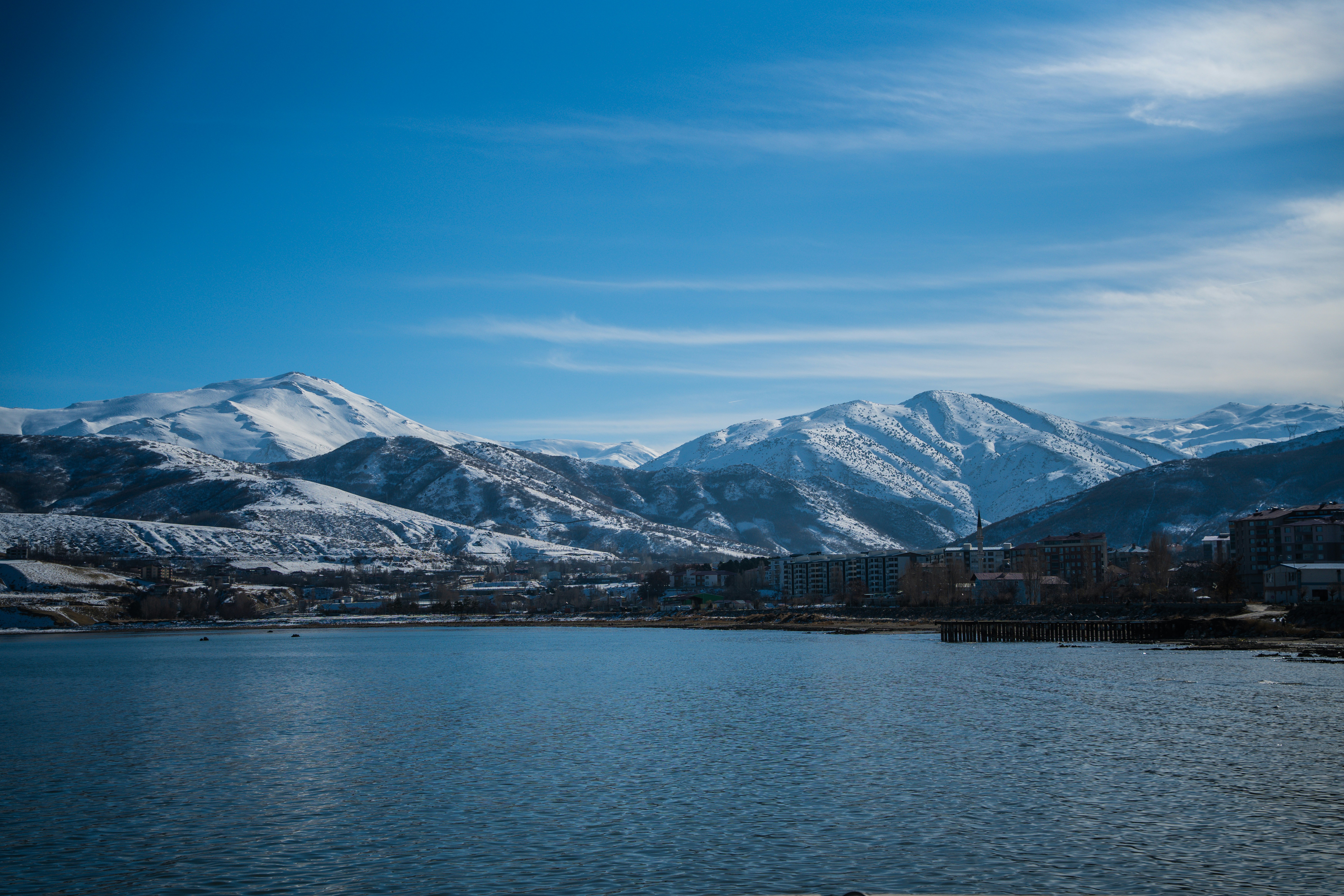 Snow-covered mountains overlook a calm blue lake.