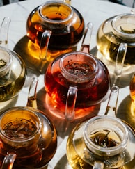 Several glass teapots filled with different teas.