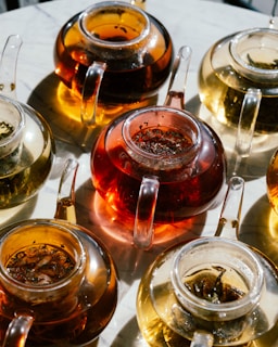 Several glass teapots filled with different teas.