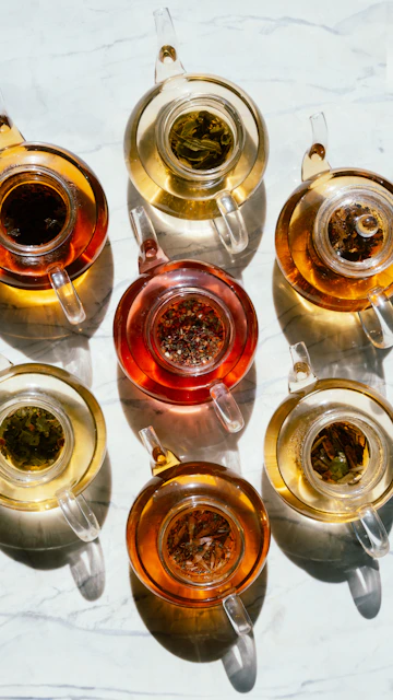 Several glass teapots filled with various teas.