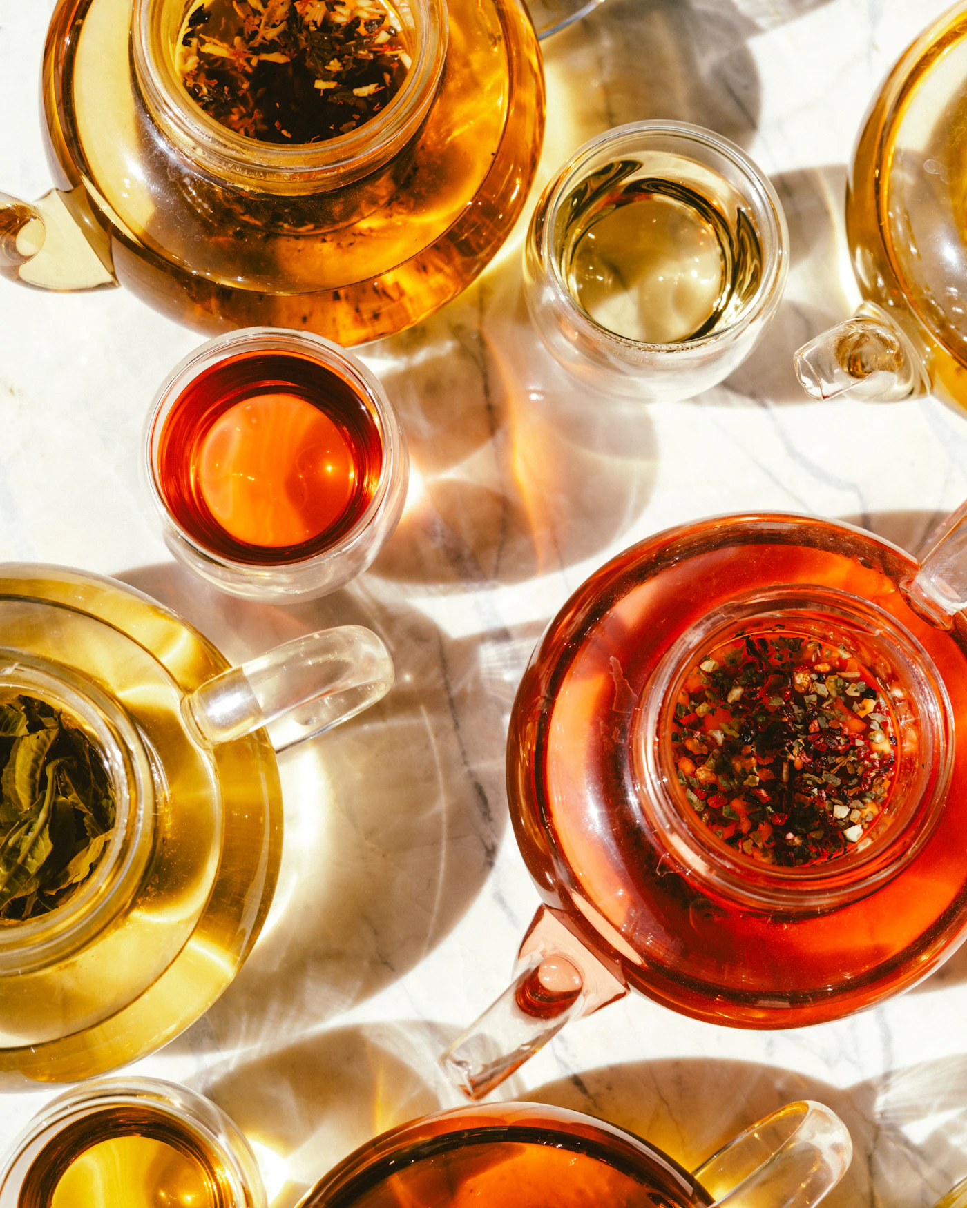 Herbal teas steeping in glass pots and cups in bright daylight