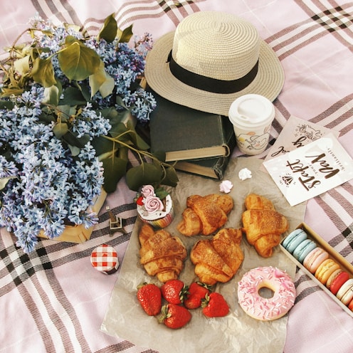 Picnic spread with pastries, strawberries, and flowers