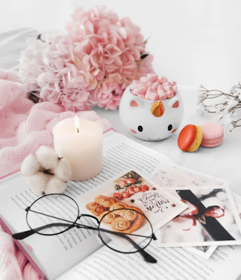 Book with glasses, candle, and pink flowers