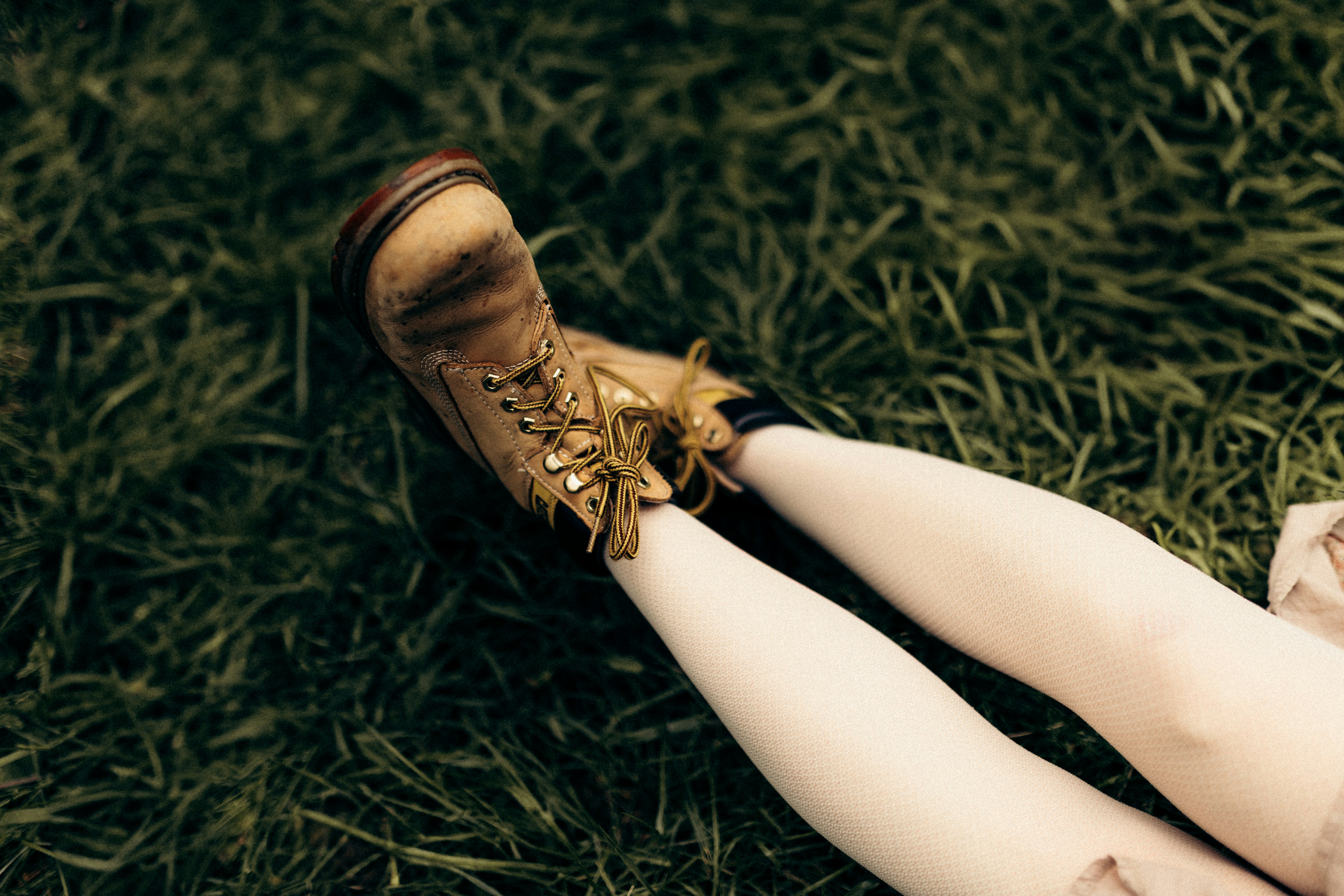 A person's legs and boots lying on grass