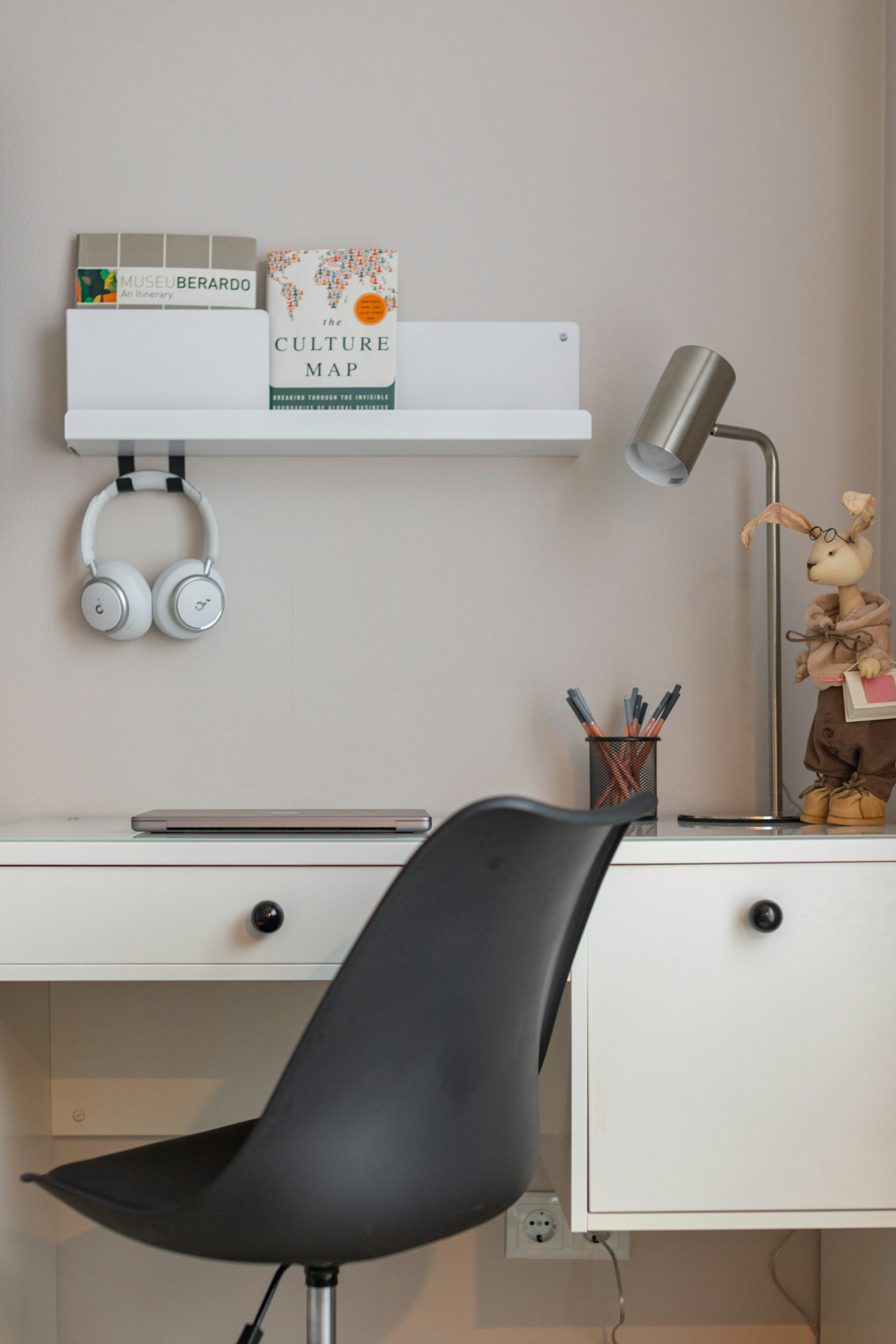 A modern desk with headphones, books, and a lamp.