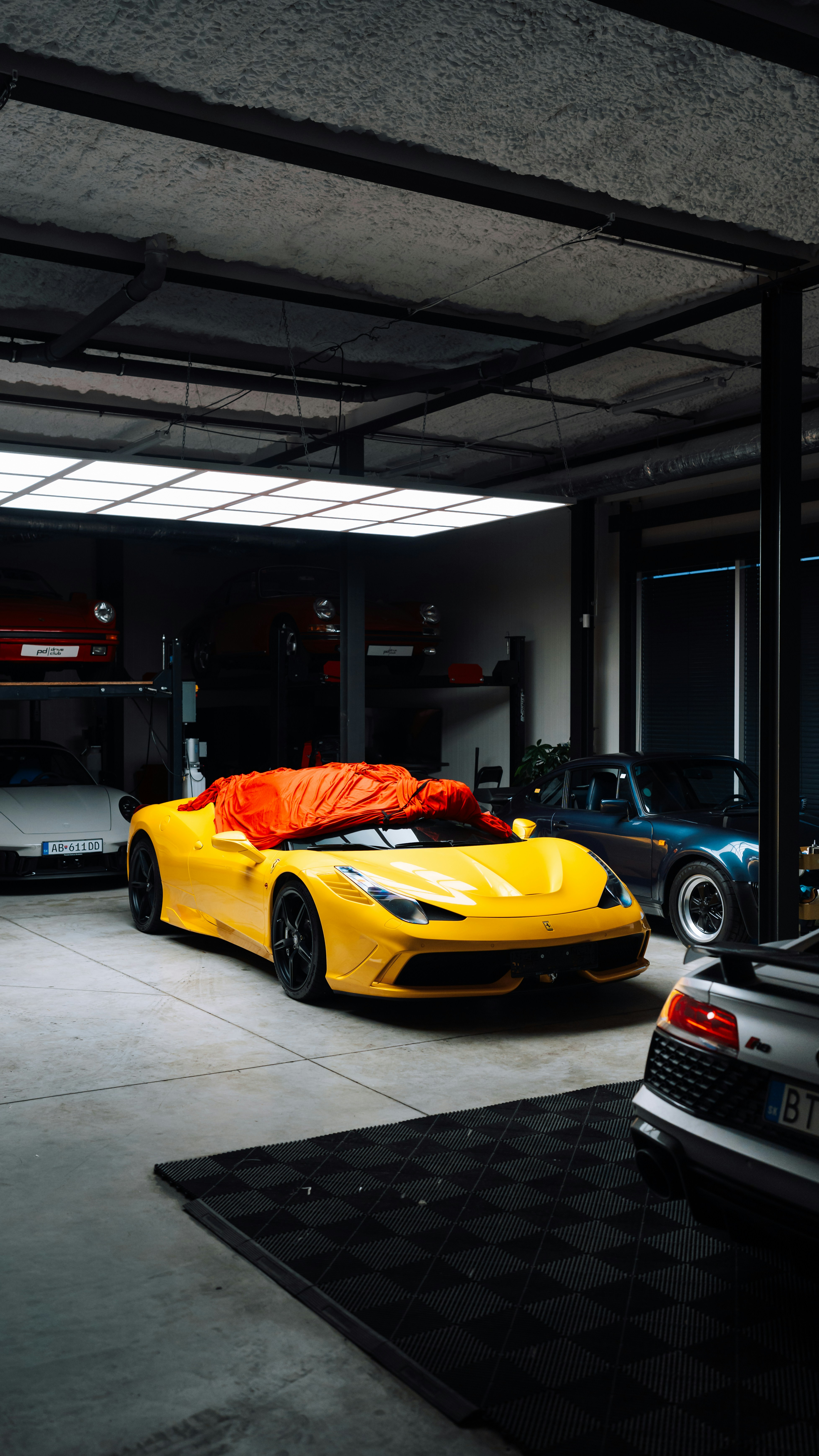 Yellow sports car covered with orange tarp in garage.