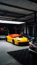 Yellow sports car covered with orange tarp in garage.