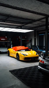 Yellow sports car covered with orange tarp in garage.