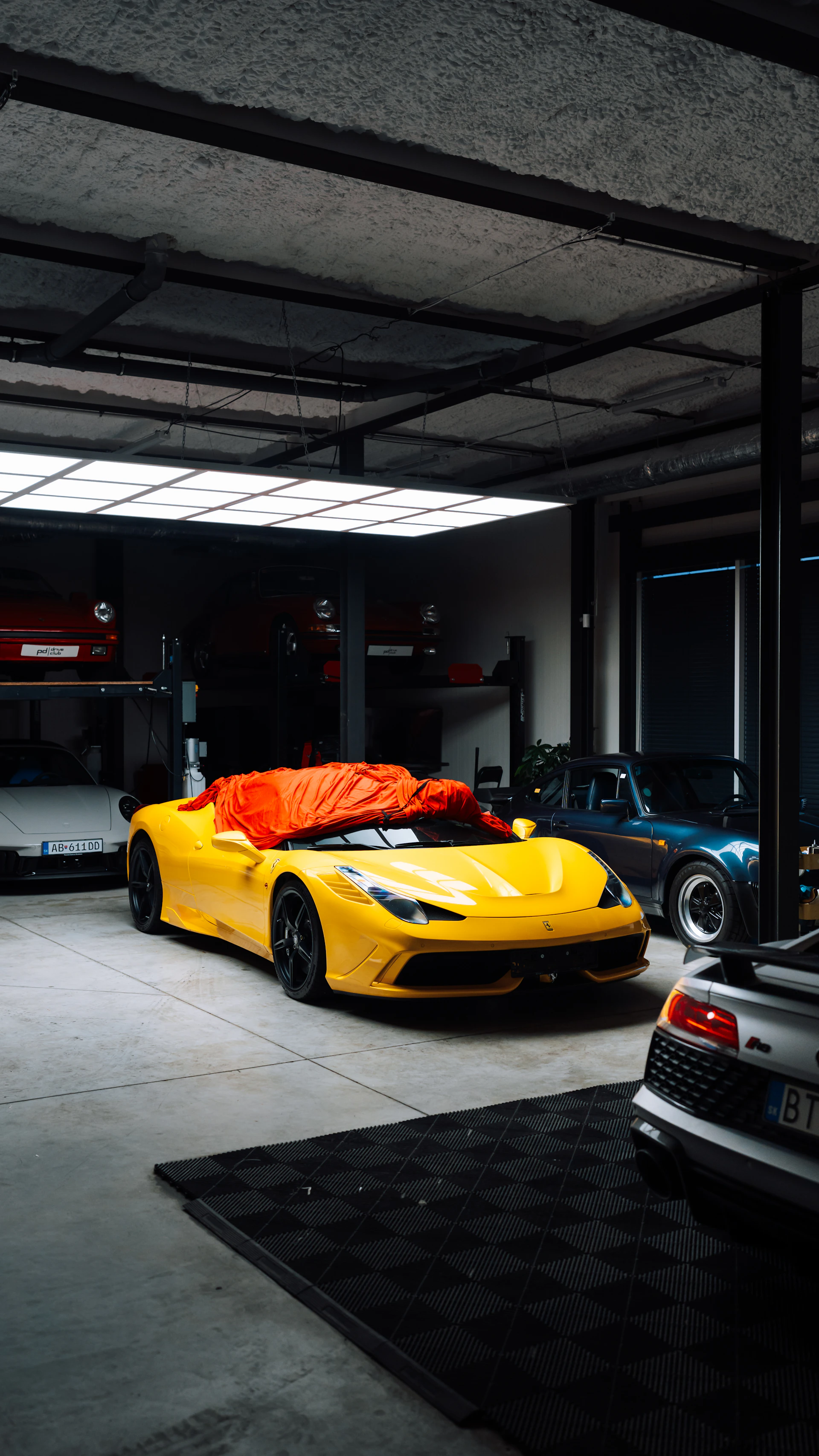 Yellow sports car covered with orange tarp in garage