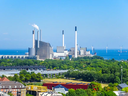 Industrial power plant with smokestacks by the ocean.