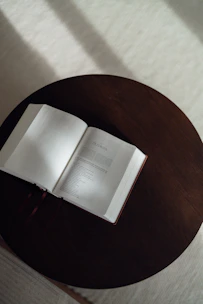 An open book rests on a dark wooden table