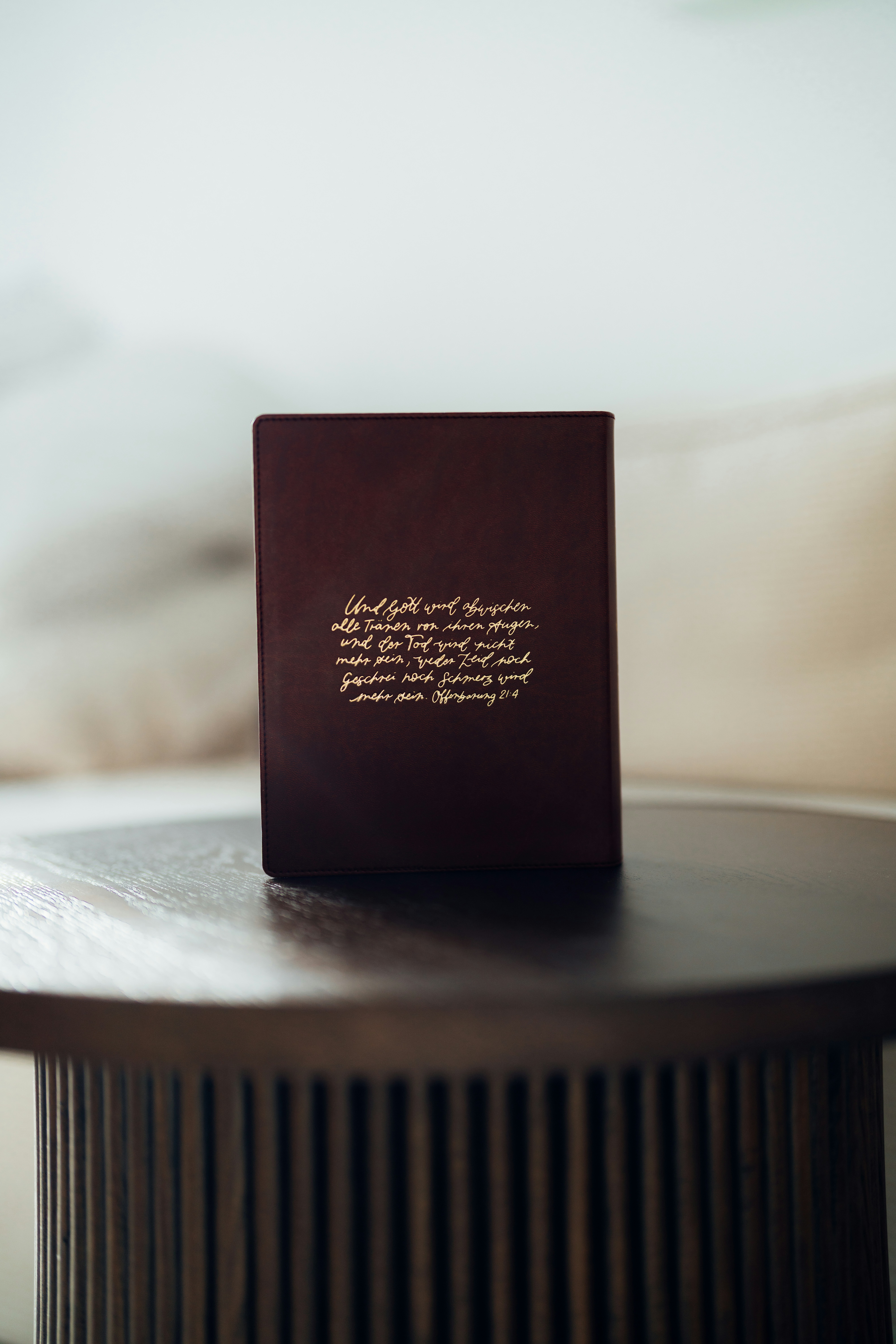 Um livro fechado com letras douradas sobre uma mesa.