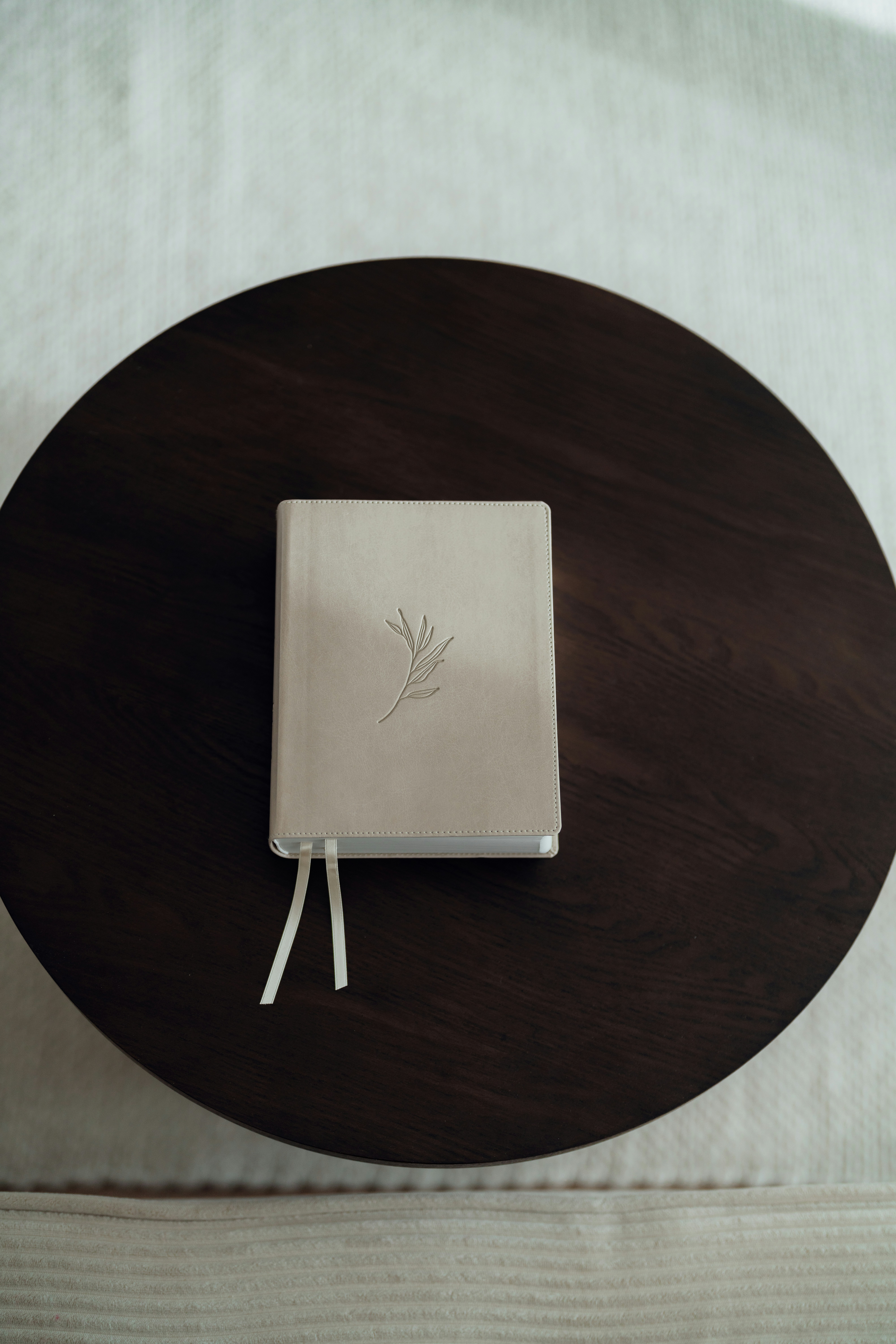 A closed white journal with a twig embossed on cover.