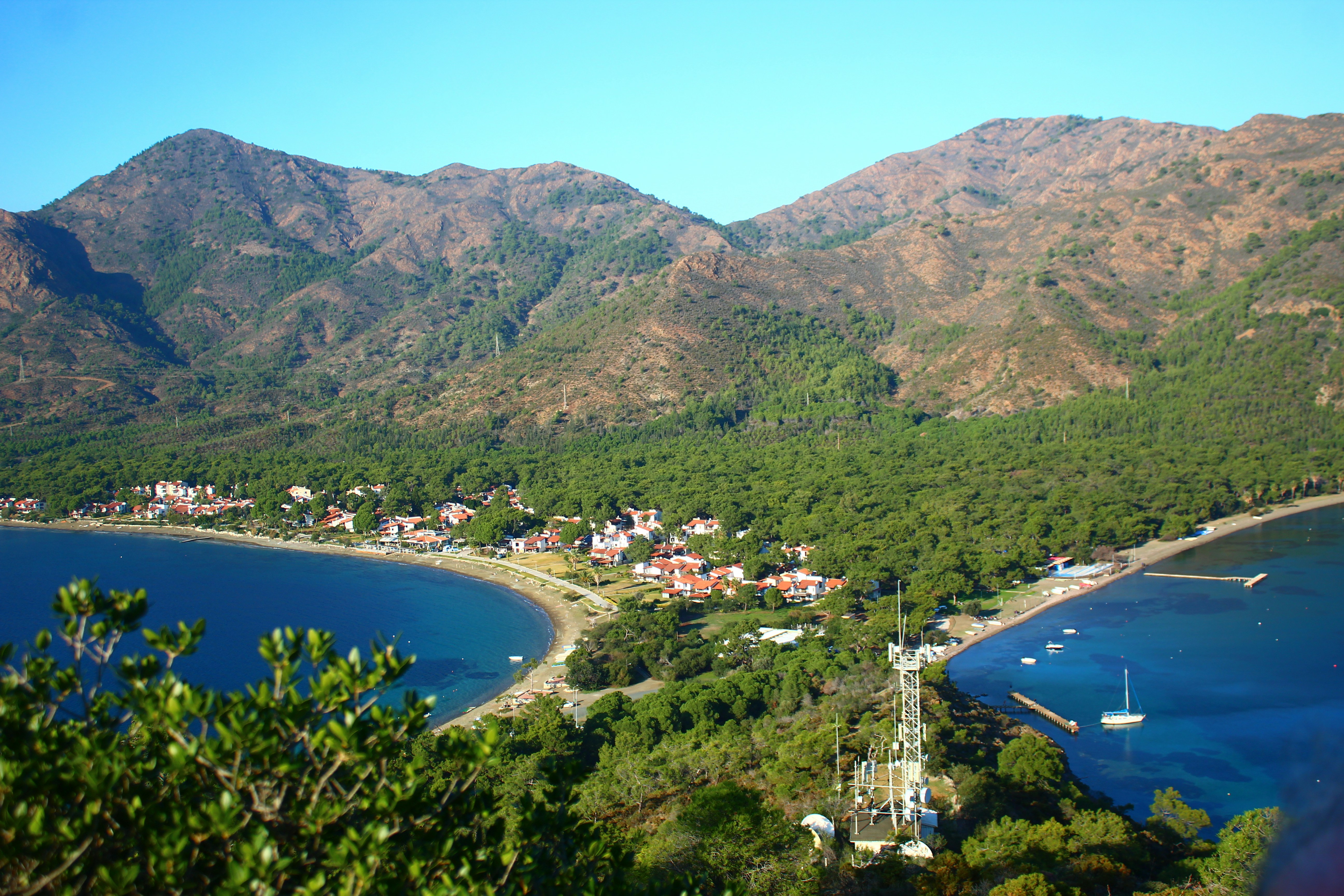 Coastal village nestled between blue bays and green mountains.