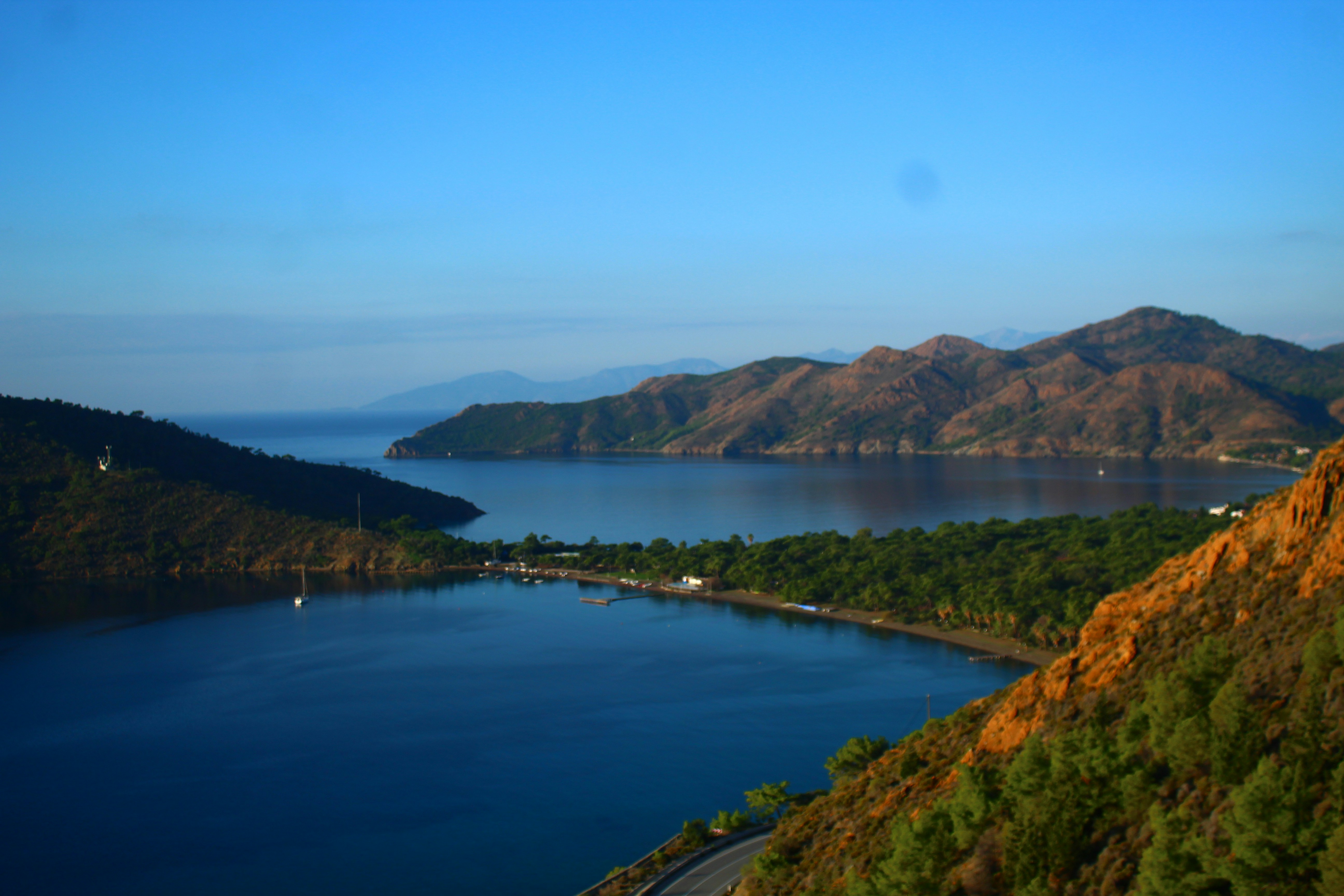 Calm blue bay surrounded by green hills and mountains.