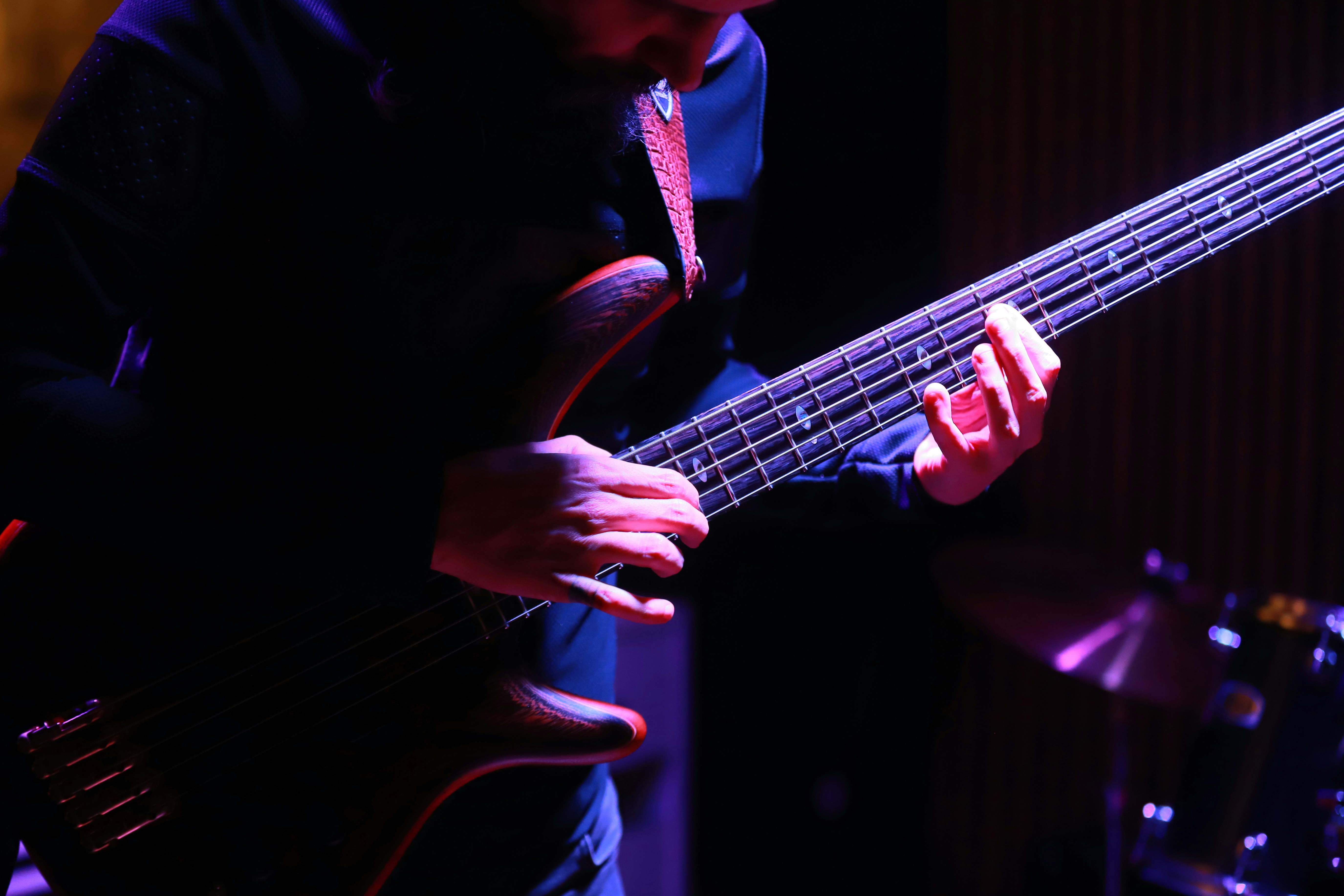 Musician playing a dark electric bass guitar.