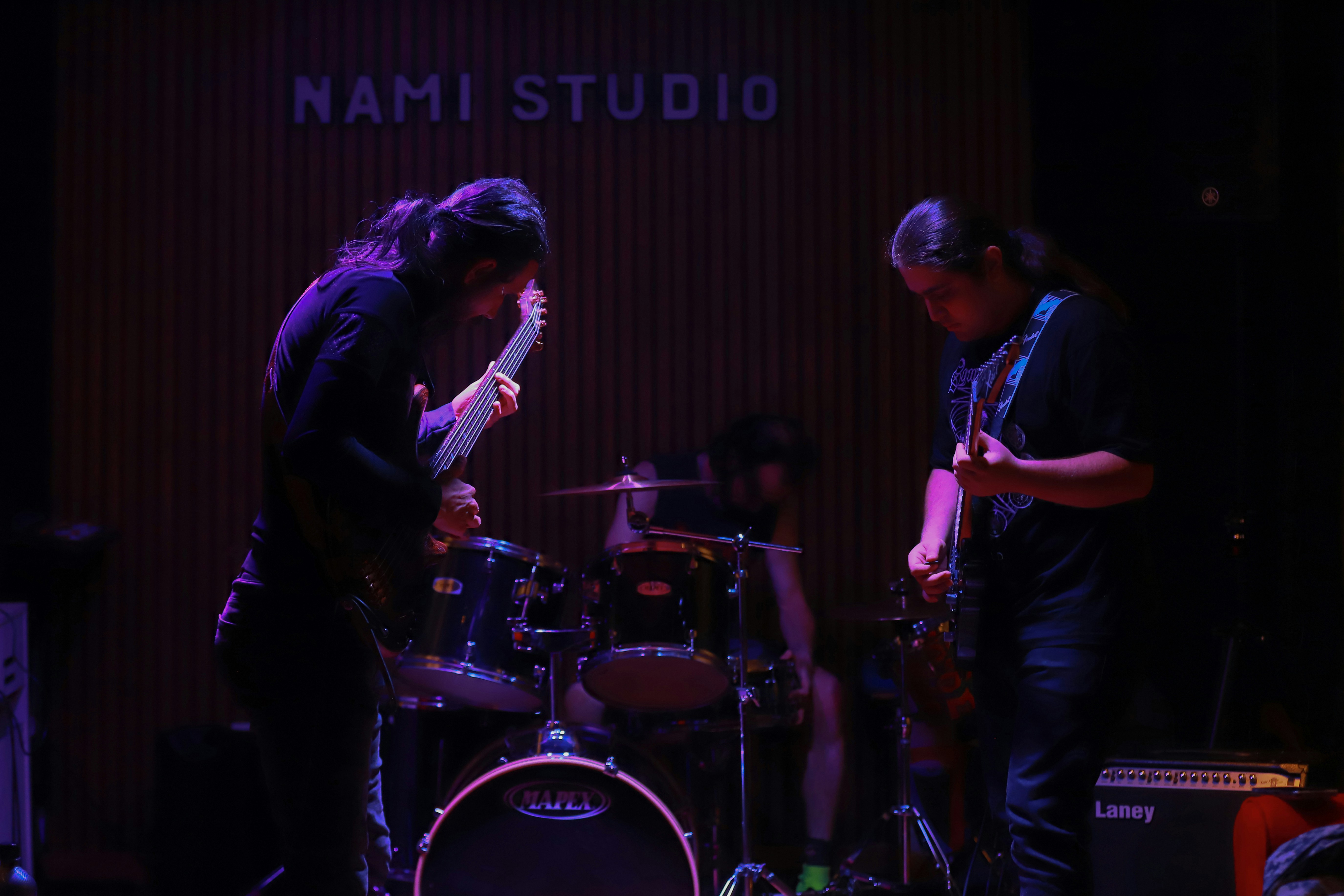 Musicians playing guitars and drums on stage.