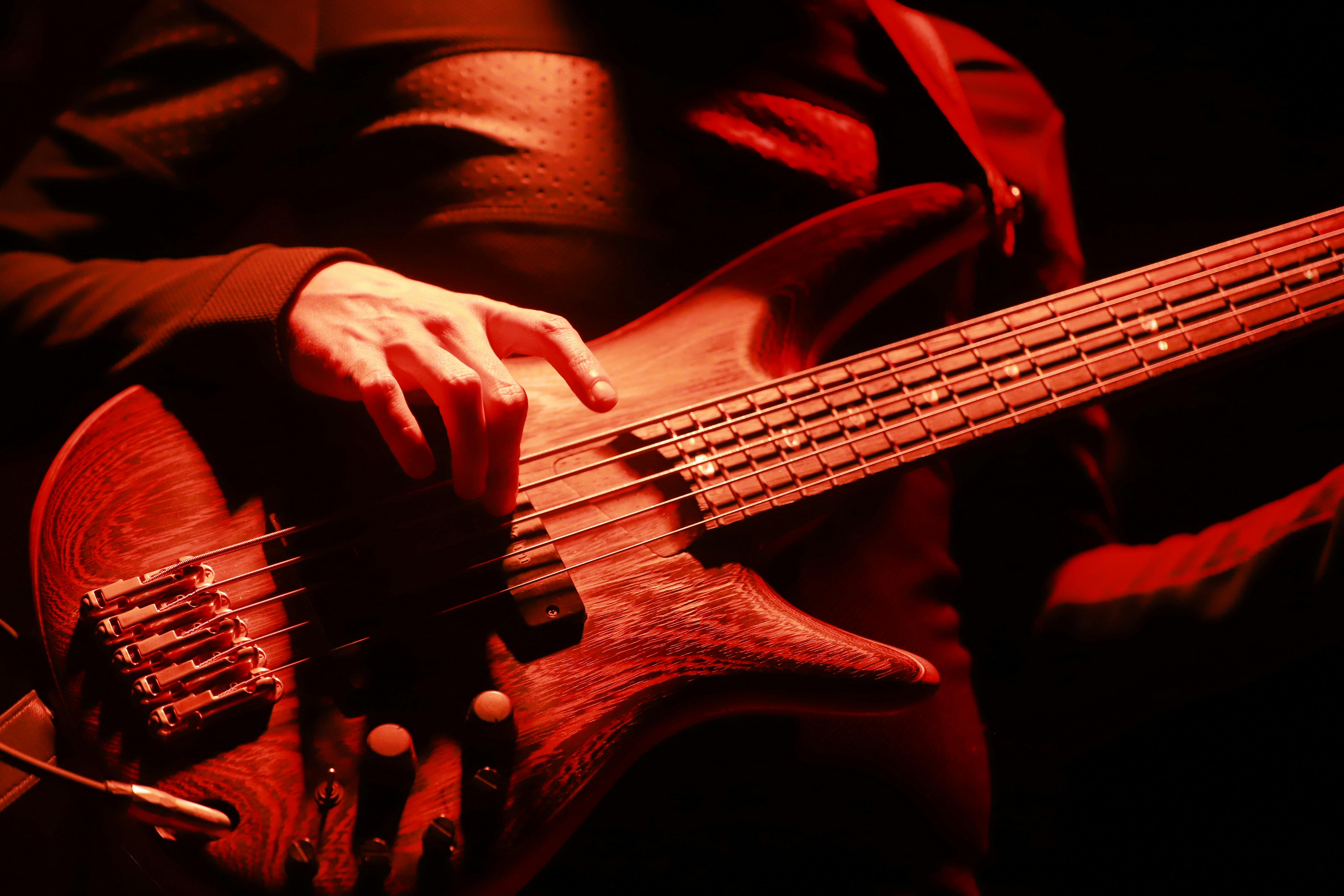 Musician playing a wooden bass guitar on stage.