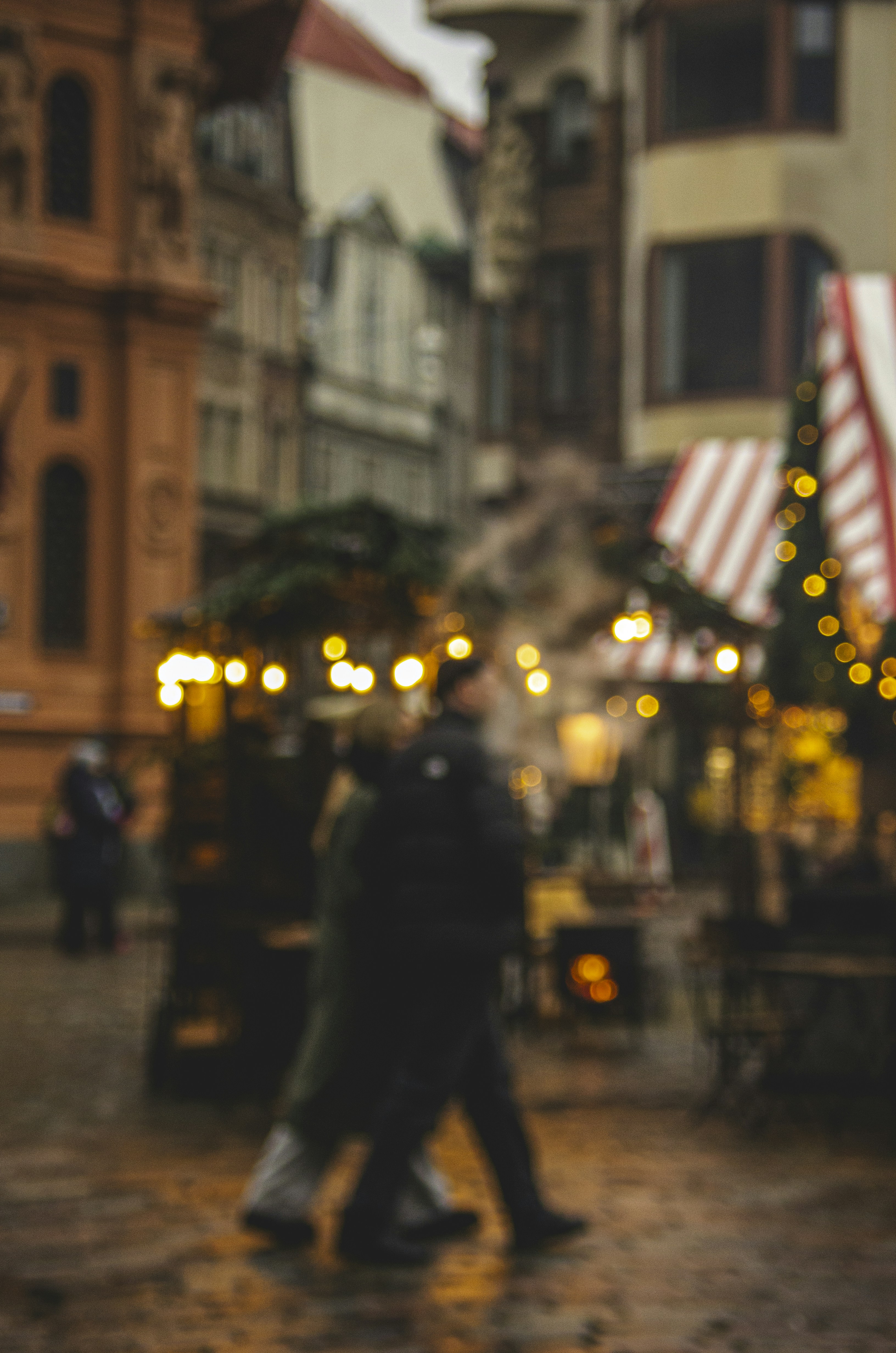 People walk through a blurred street market at dusk.