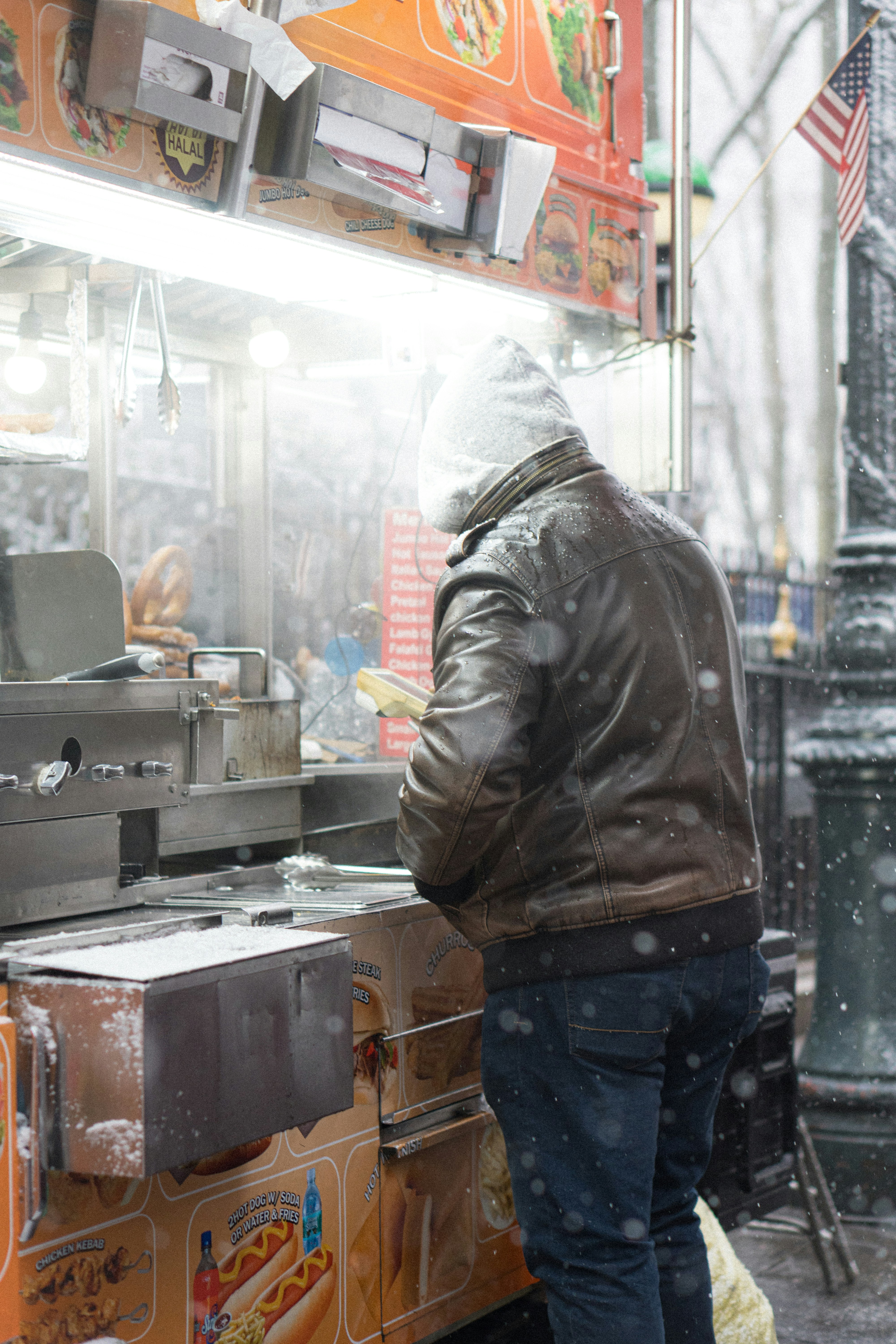 Man buying food from a street cart in snow.