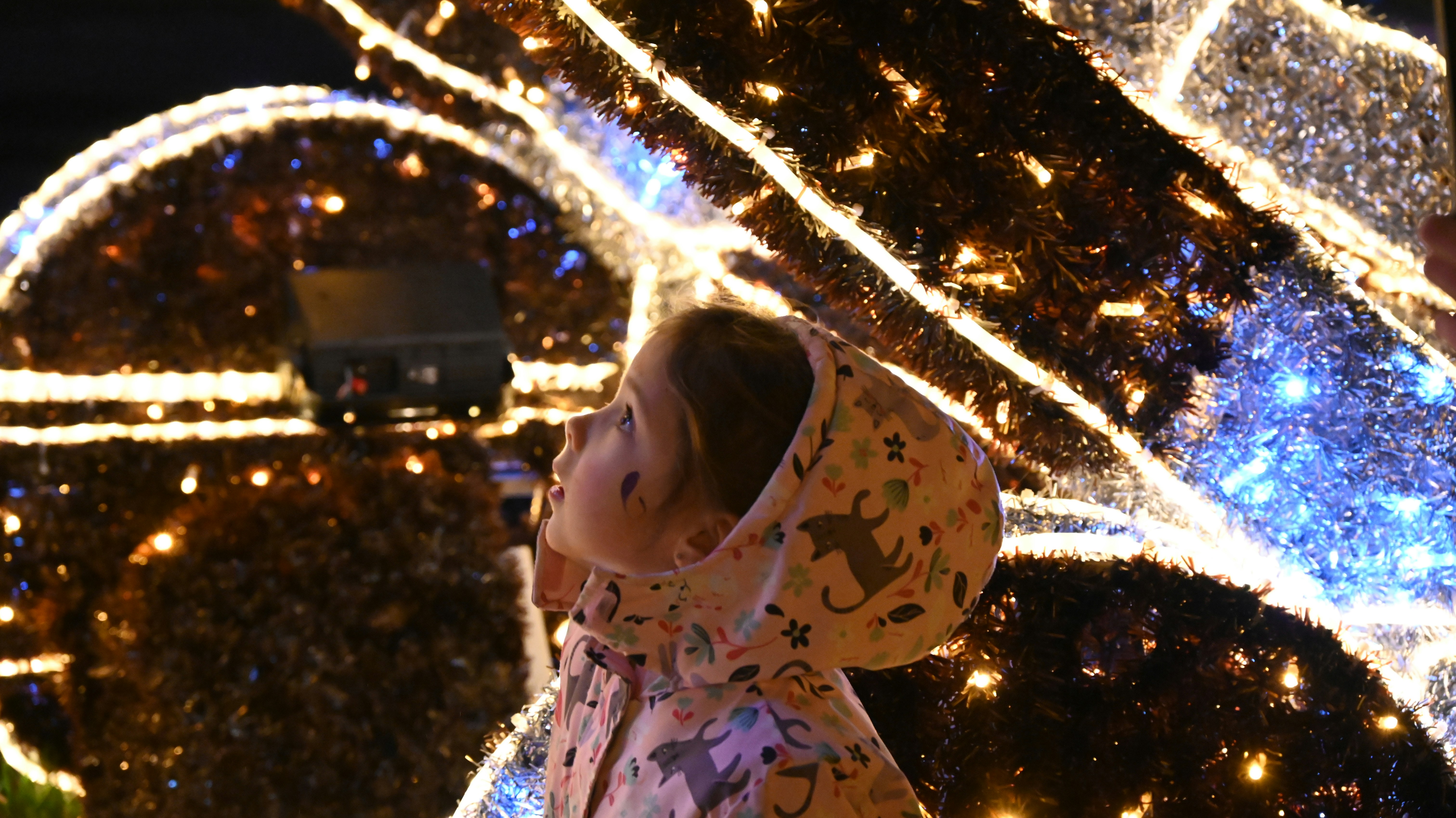 Child looking up at illuminated christmas decorations