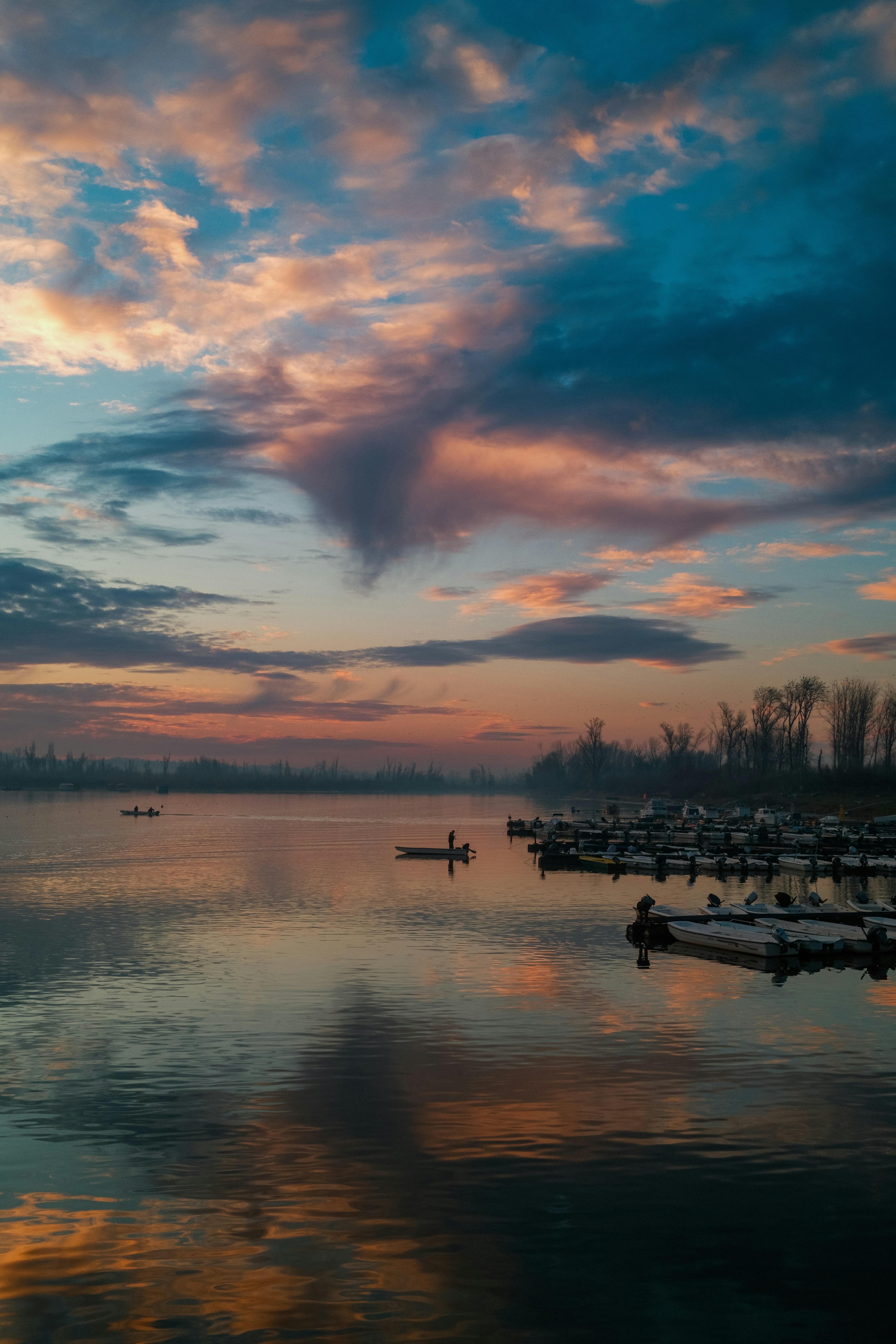 Sunrise over a calm lake with boats docked boats.