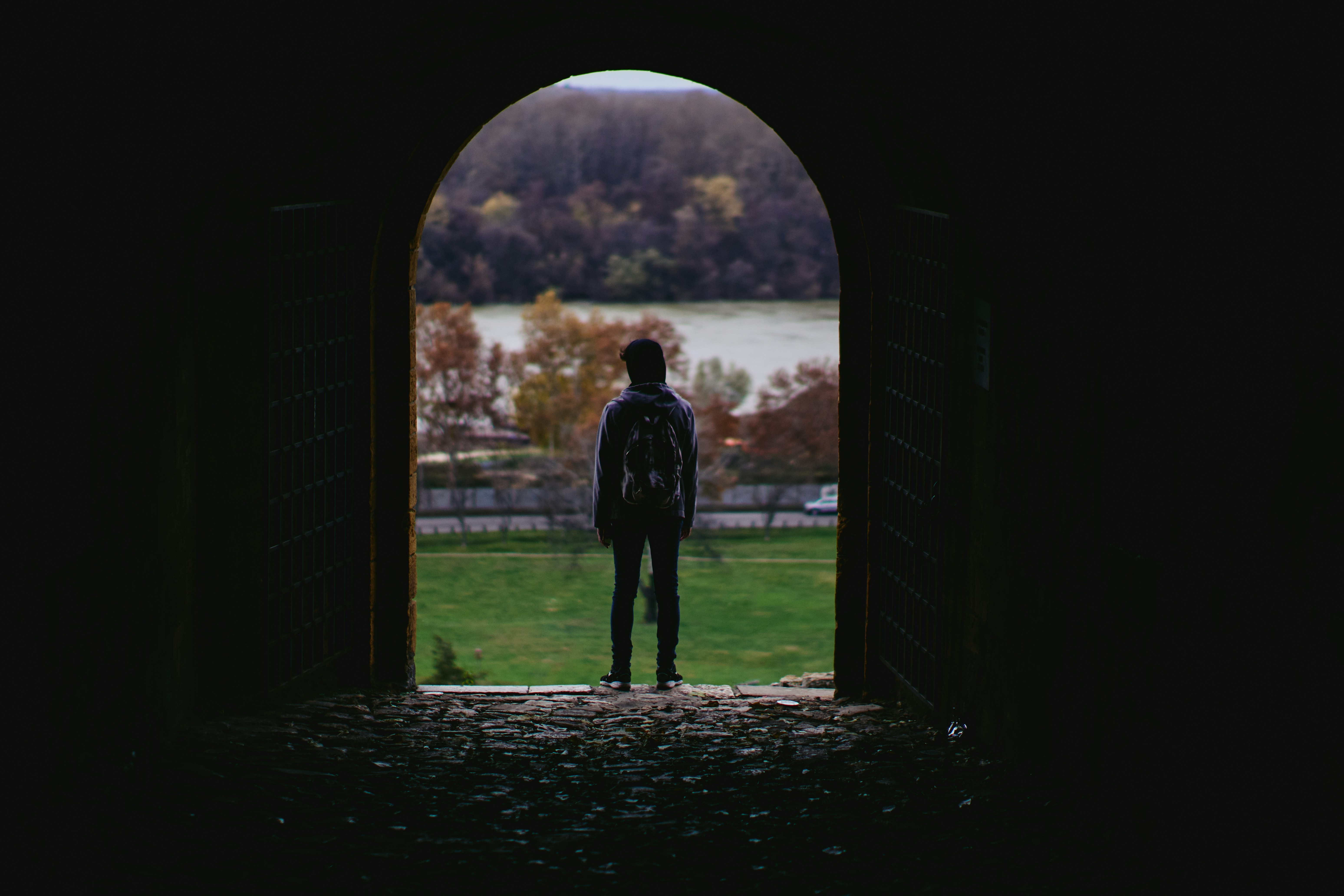Person with backpack stands in arched doorway looking outside