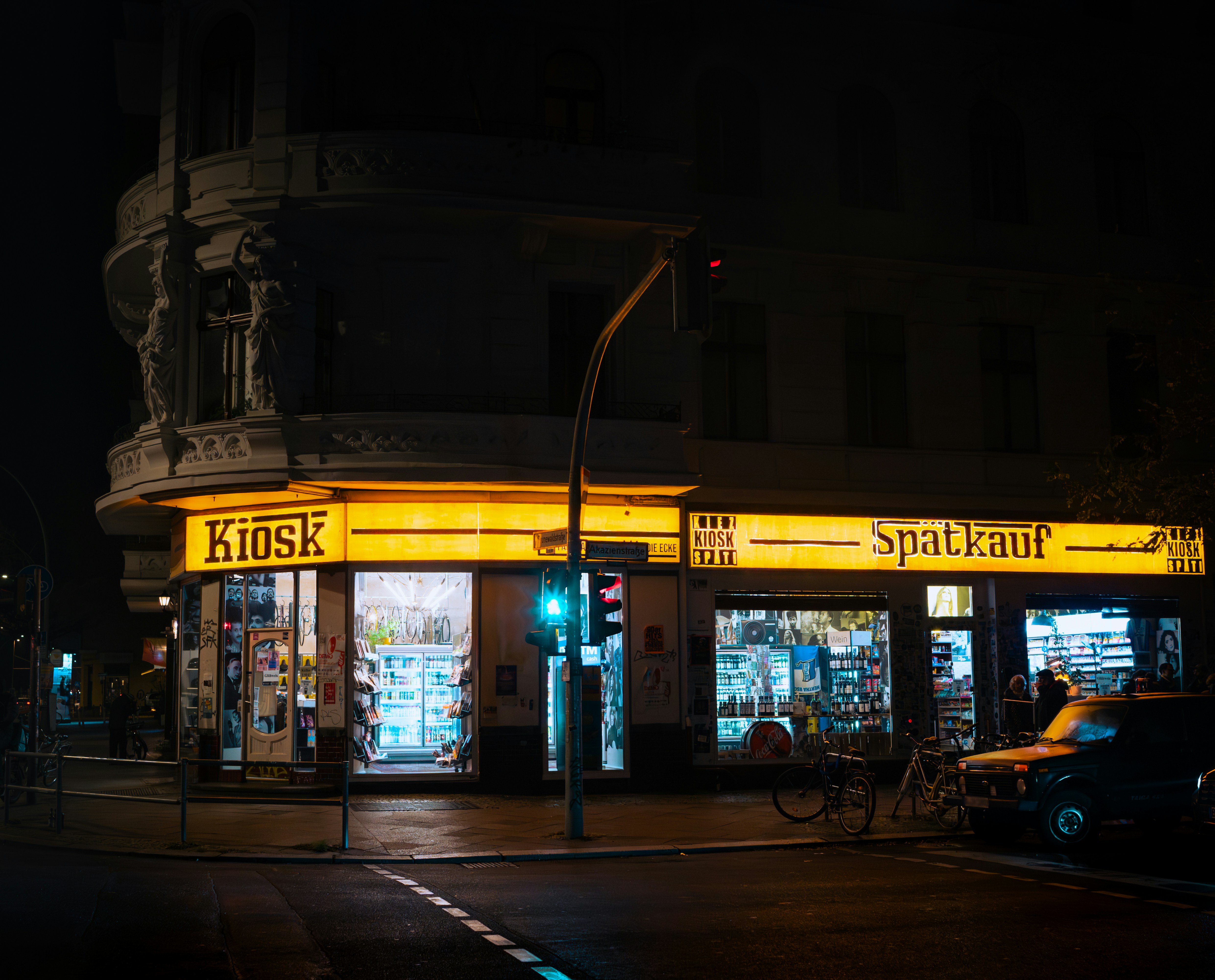 A brightly lit kiosk on a Berlin street corner during nighttime. Yellow, Yellow Neon