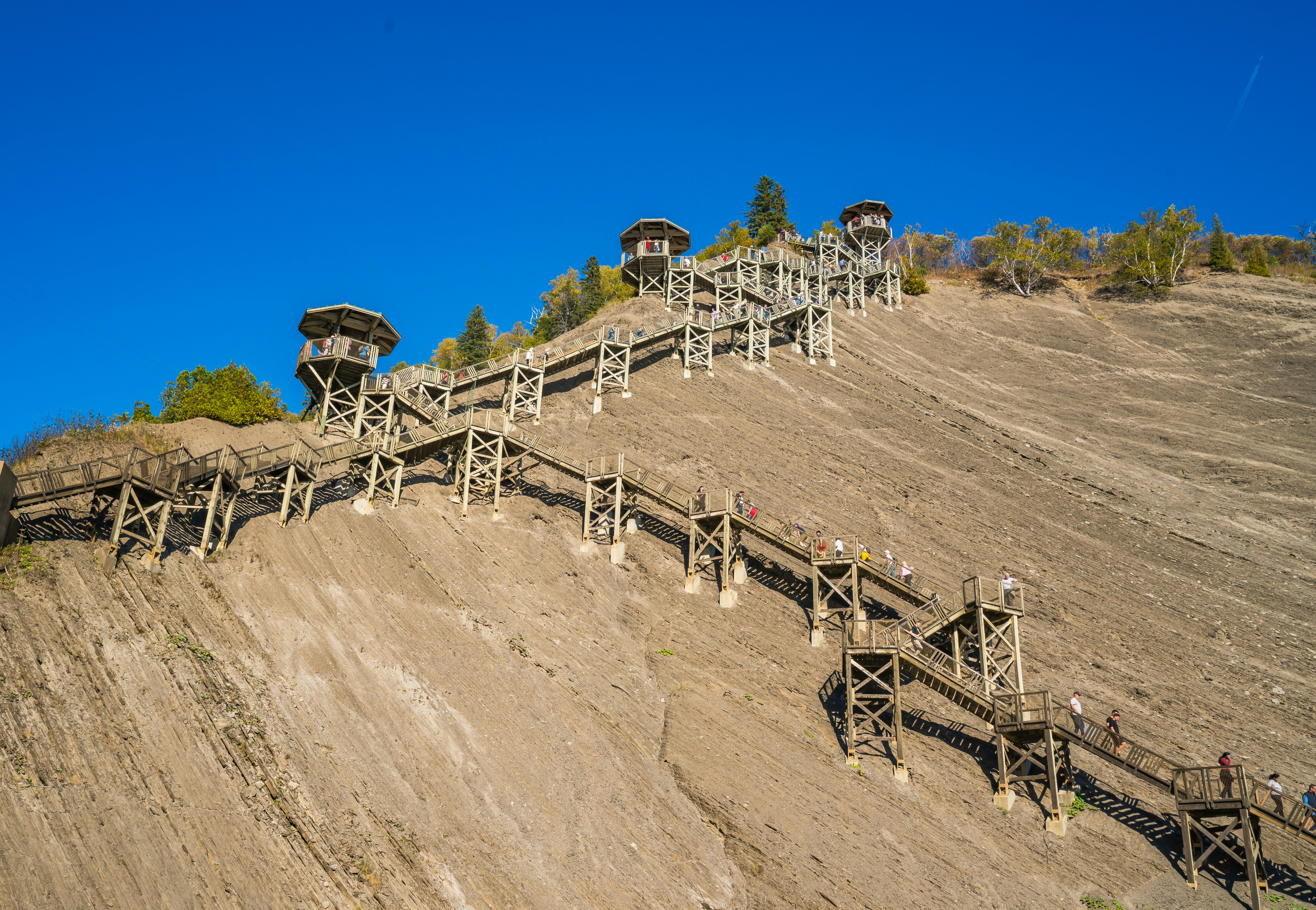 Wooden stairs ascend a rocky mountainside with observation towers.