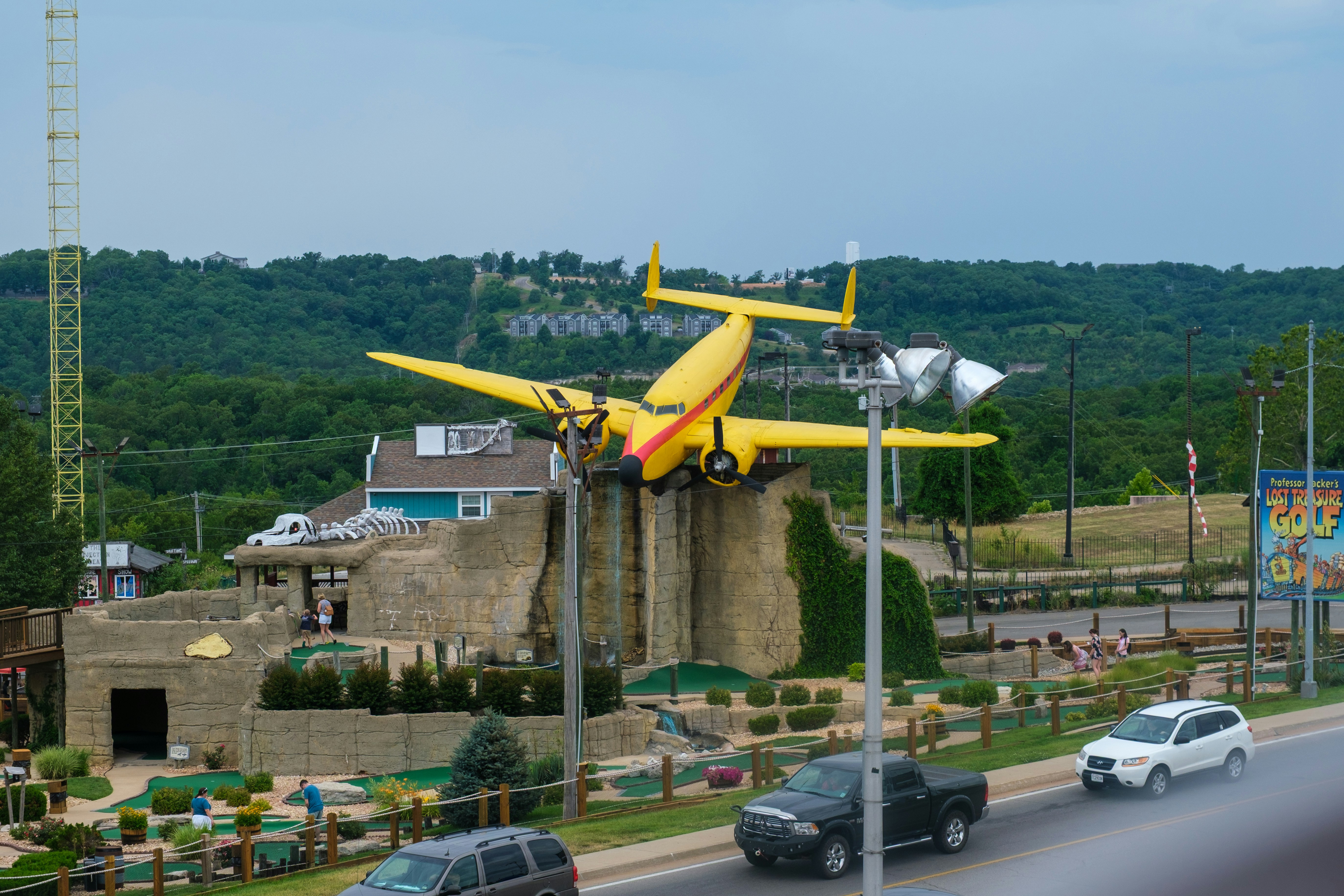 Yellow airplane sculpture on display with cars driving by.