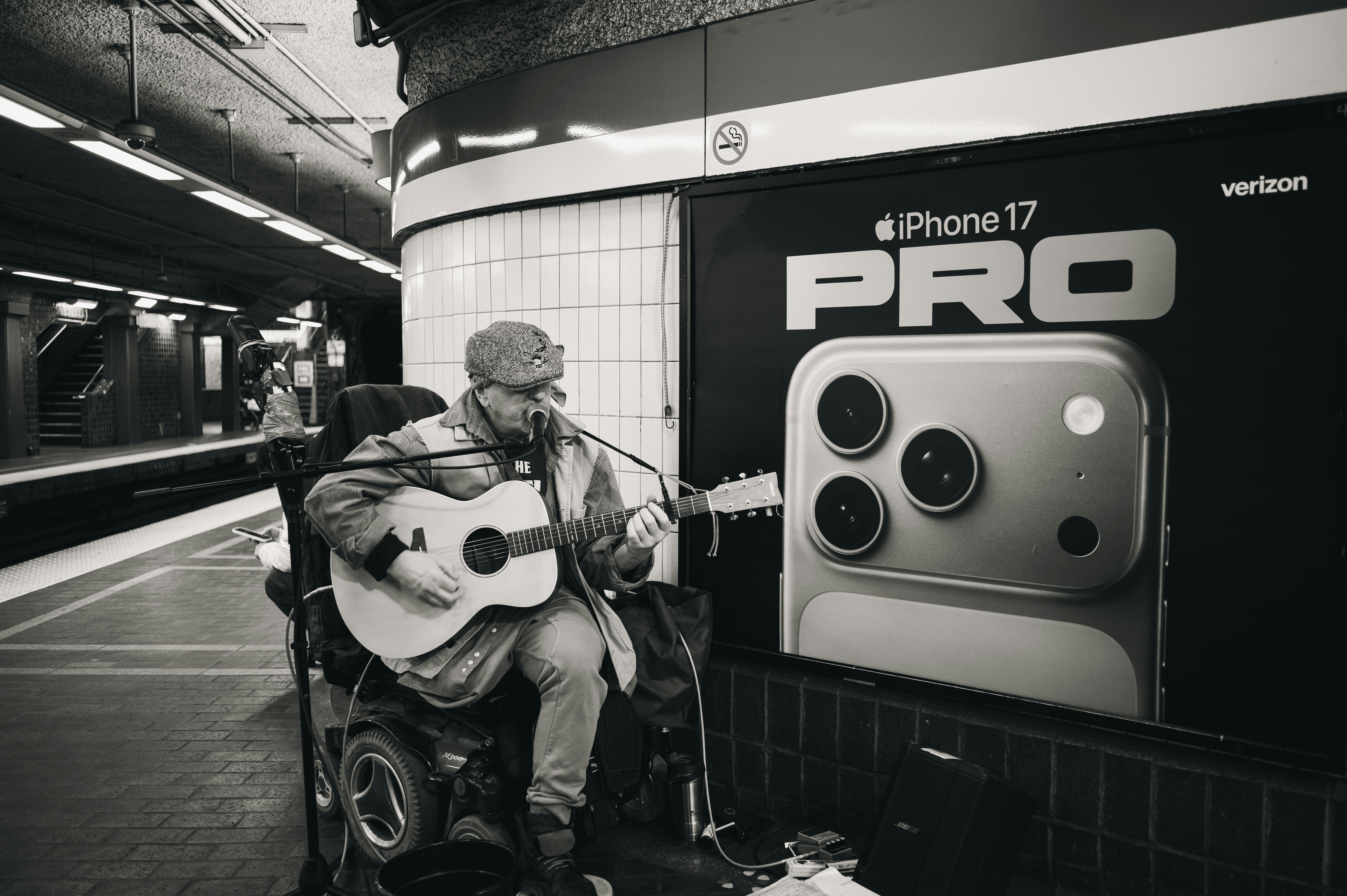 Man in wheelchair plays guitar near subway ad