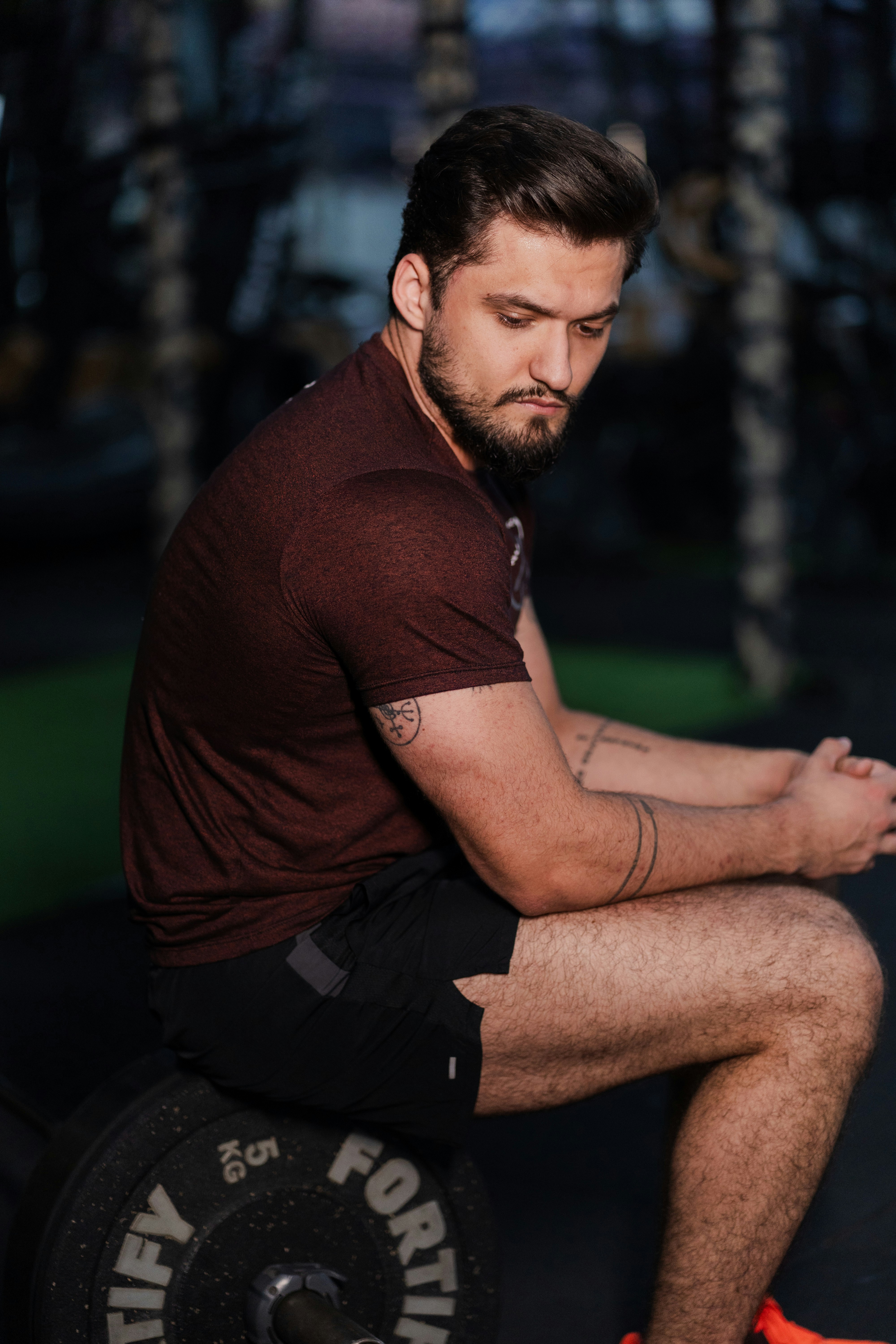 Uomo seduto su una piastra di pesi in palestra