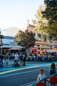 People walking on a street with outdoor dining areas.