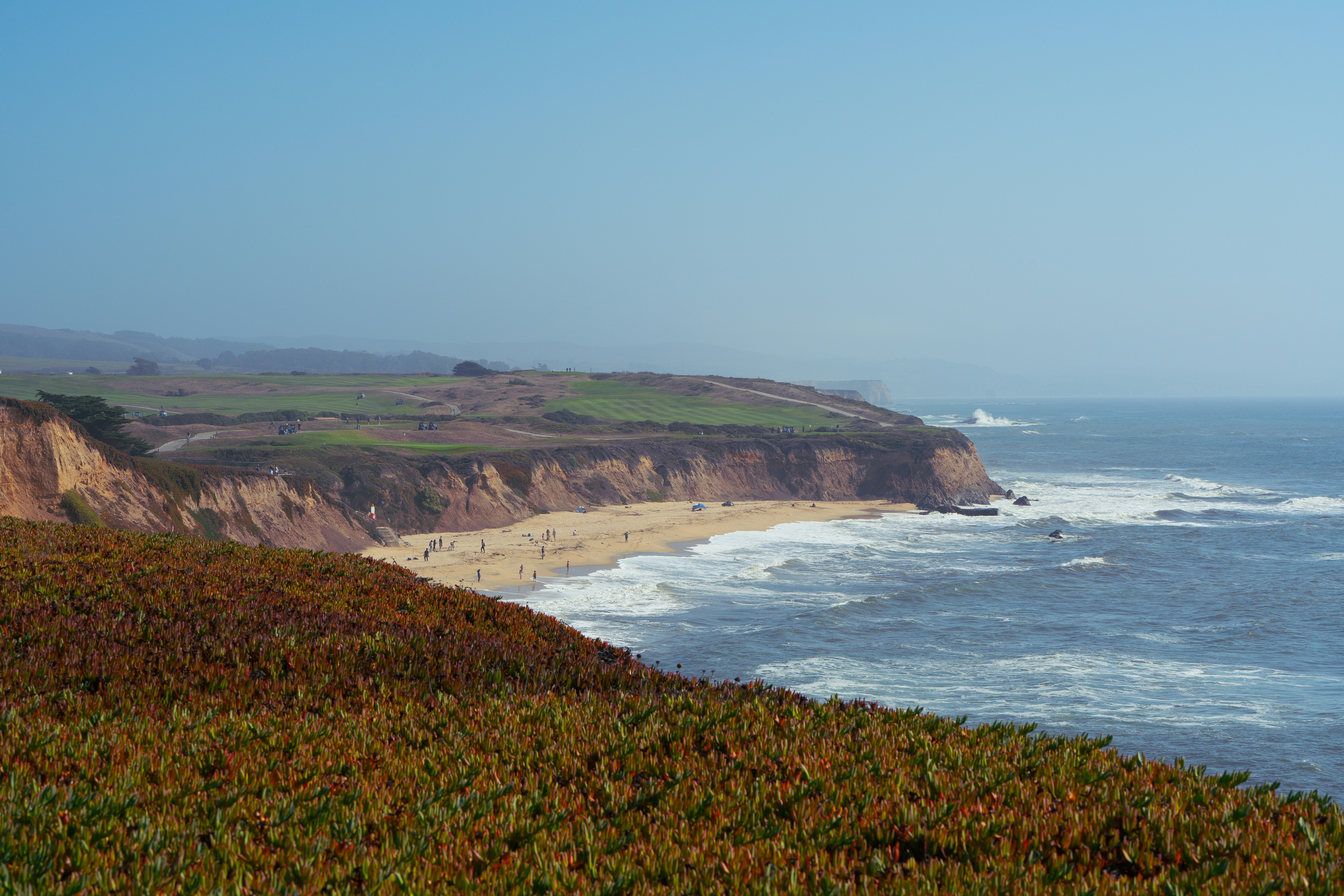 Coastal cliffs with ocean waves and sandy beach.