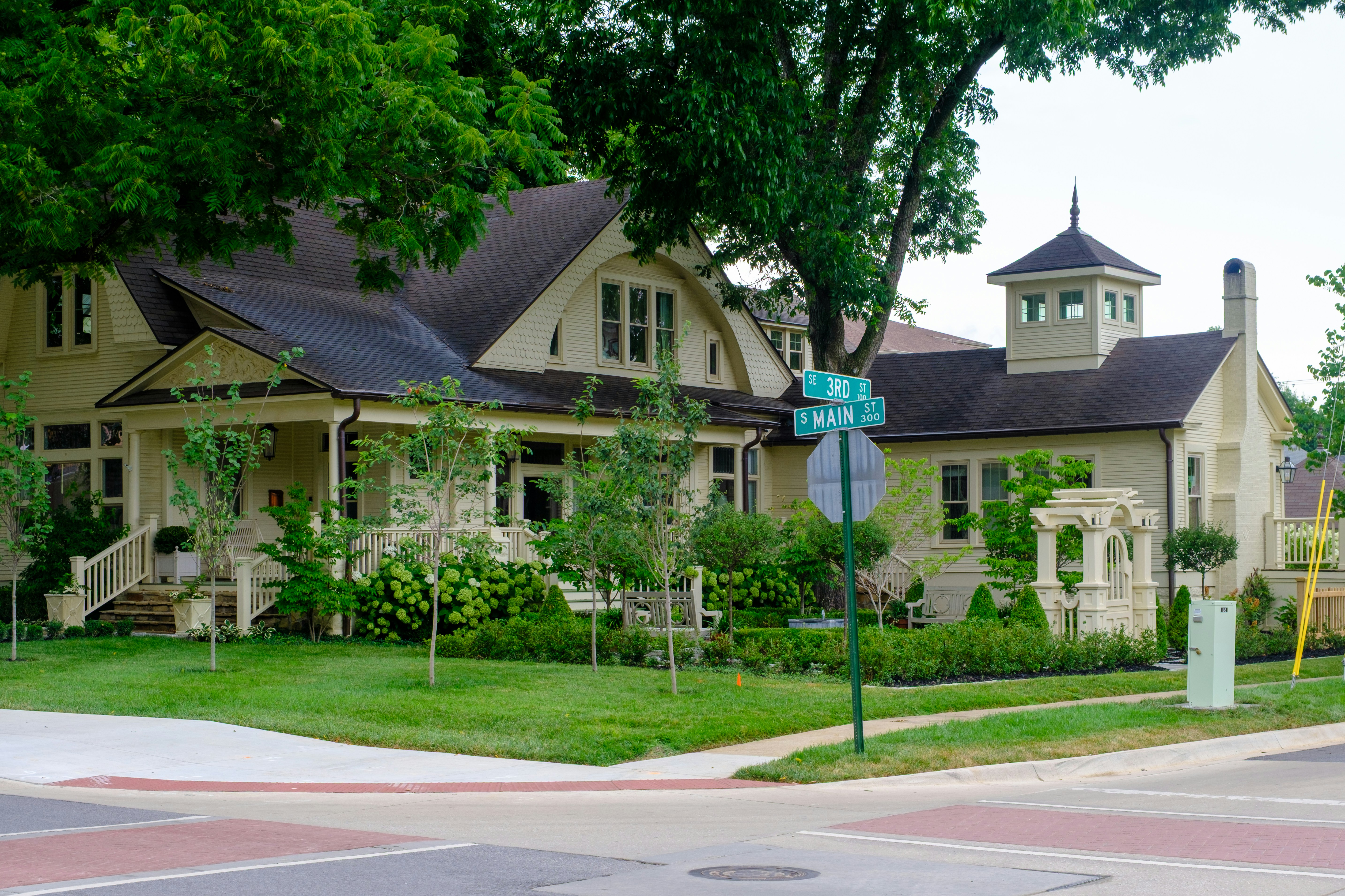 A charming yellow house with a porch and garden.
