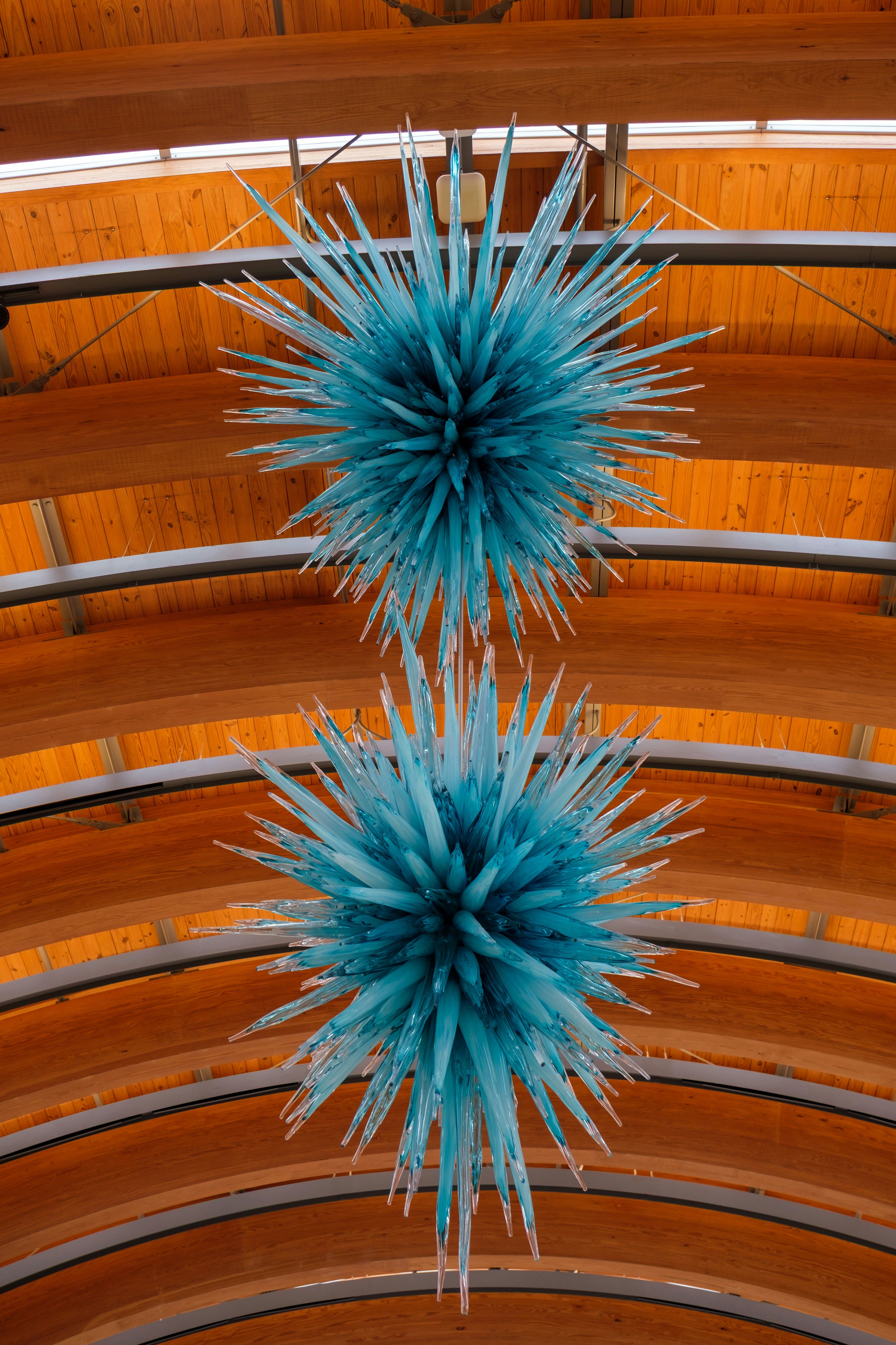 Two blue spiky chandeliers hanging from wooden ceiling