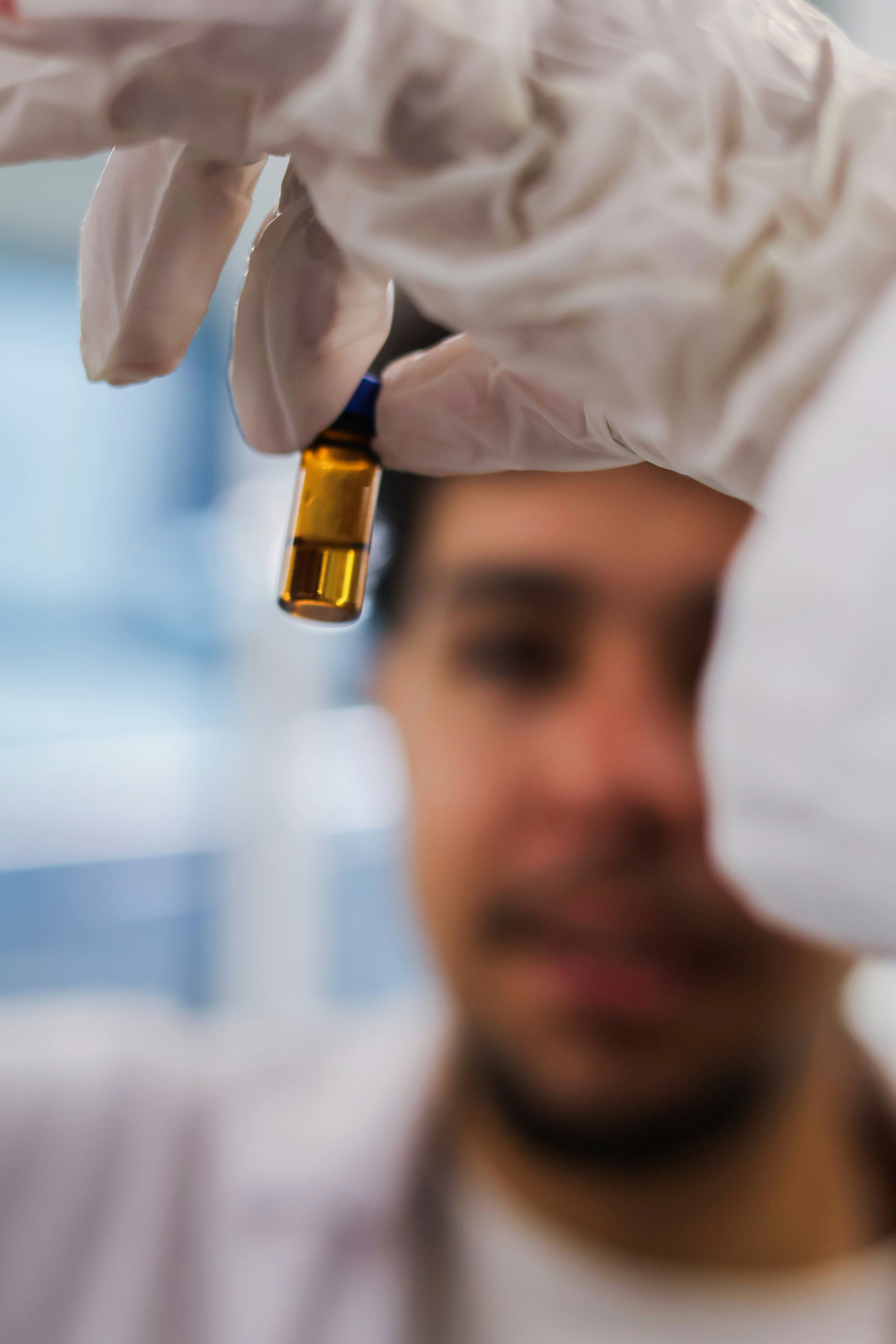 Scientist holding a small amber vial with liquid.