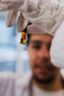 Scientist holding a small amber vial with liquid.