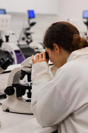 Scientist looking through a microscope in a lab.