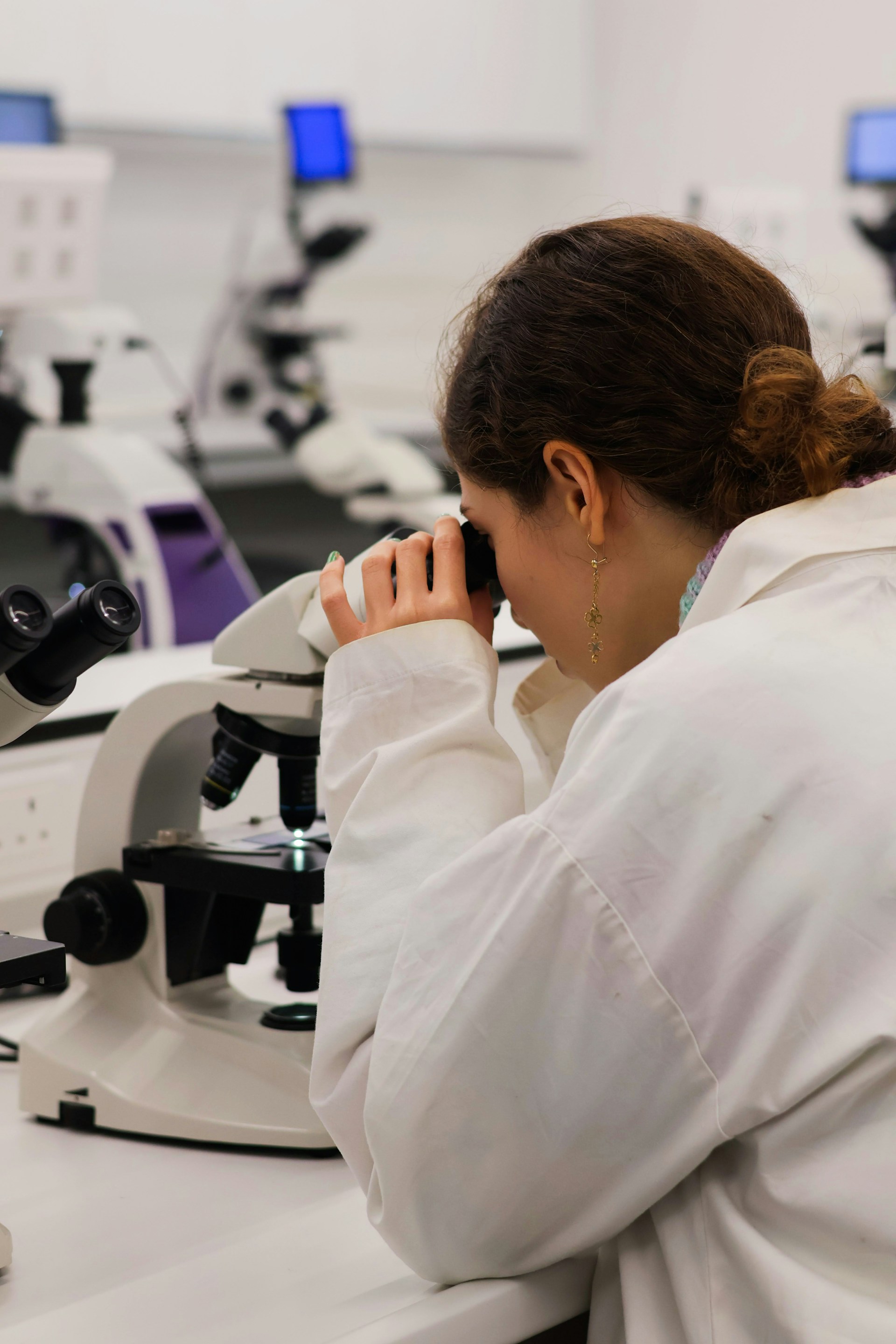 Scientist looking through a microscope in a lab.