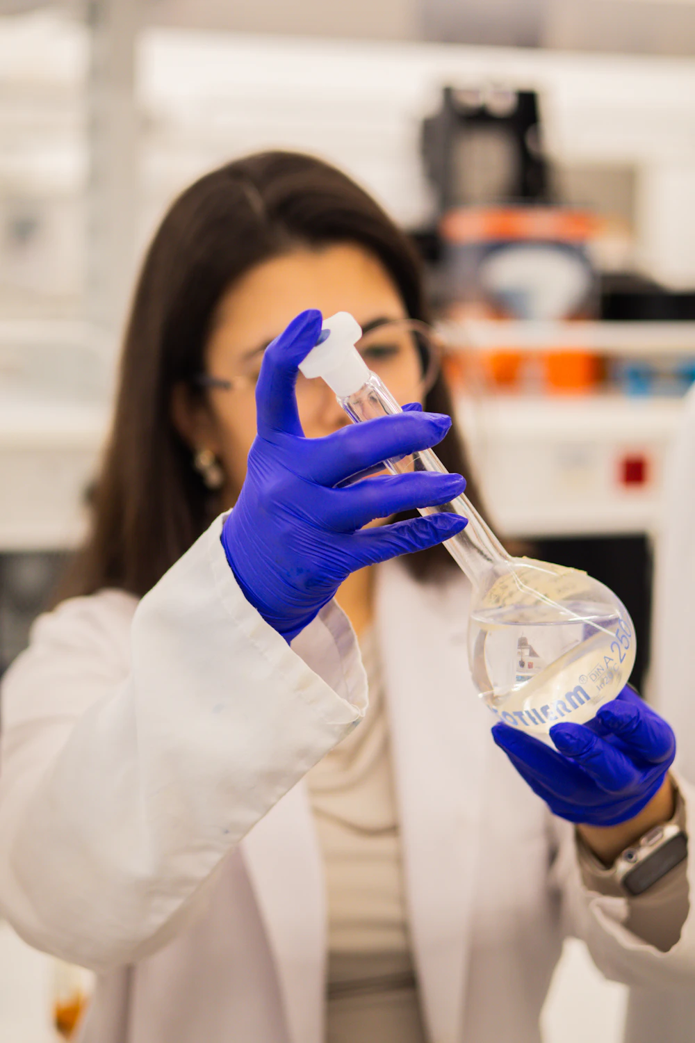 Scientist holding a flask of liquid inside a lab-ready suite