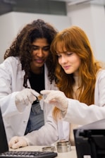 Two women in lab coats examine a sample