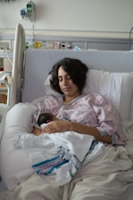 Mother holding her newborn baby in hospital bed