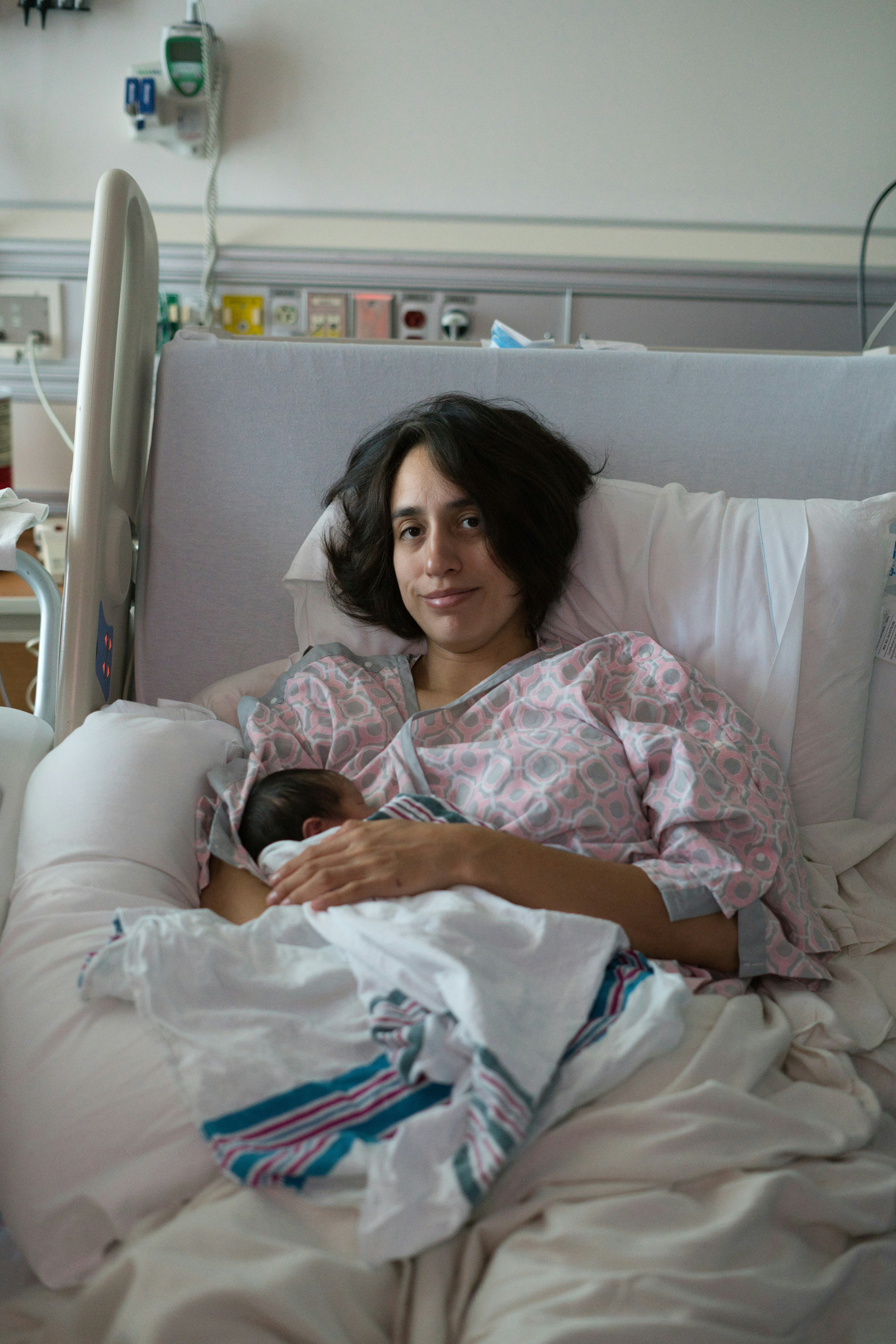 Mother holding her newborn baby in a hospital bed.
