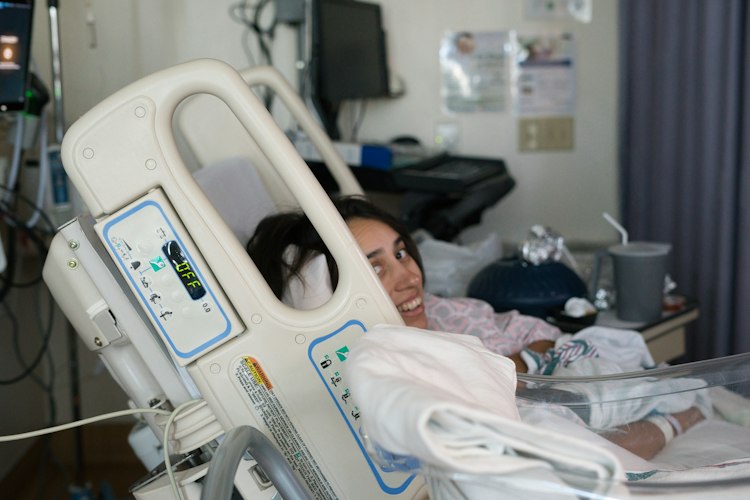 A hospital care team in scrubs conferring quietly in a labor and delivery ward hallway