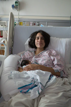 Mother holding newborn baby in hospital bed.