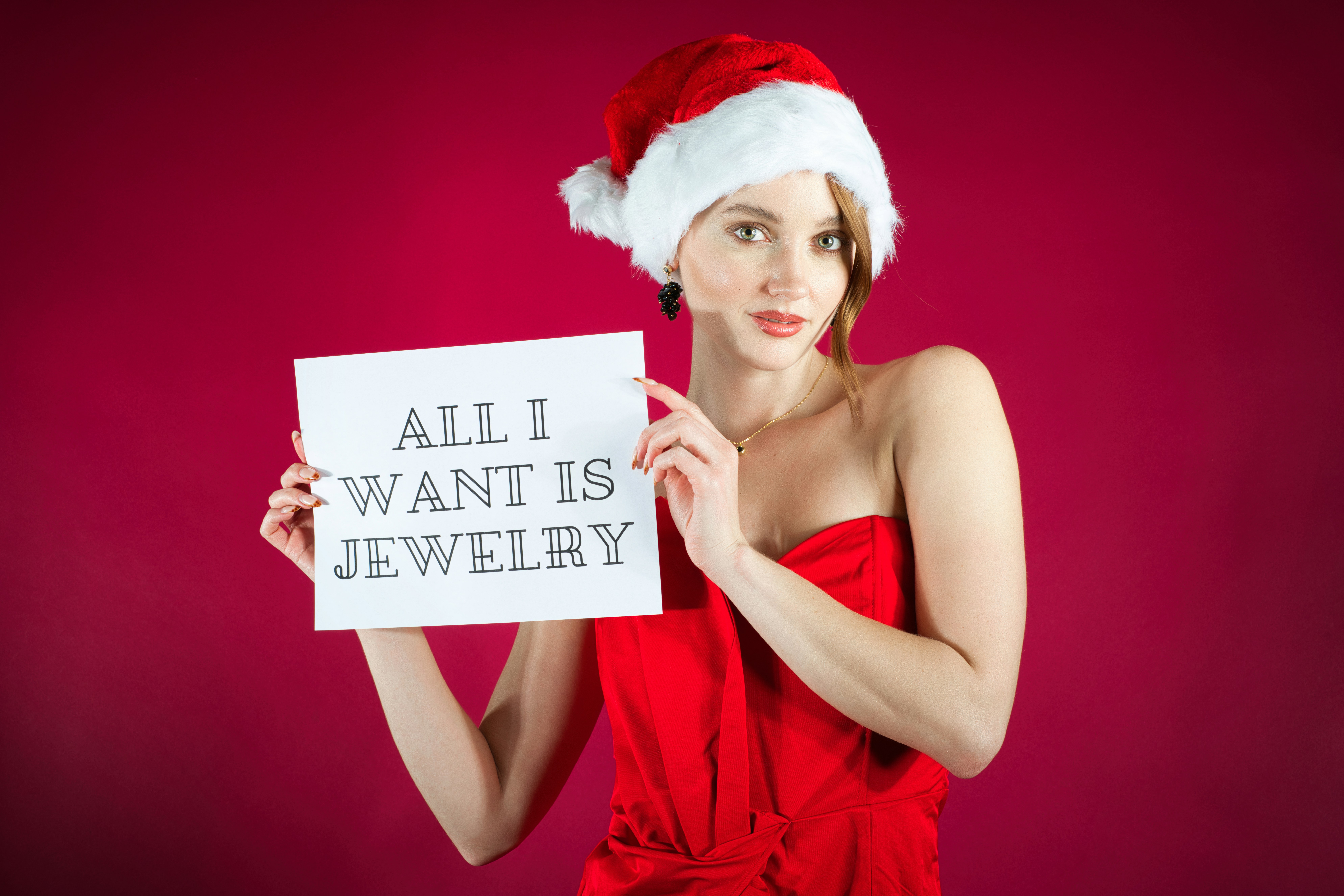 Woman in santa hat holding sign for jewelry