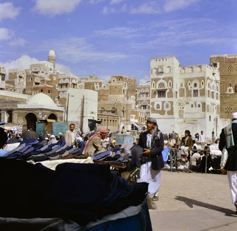 People gathered in a bustling marketplace with traditional buildings.