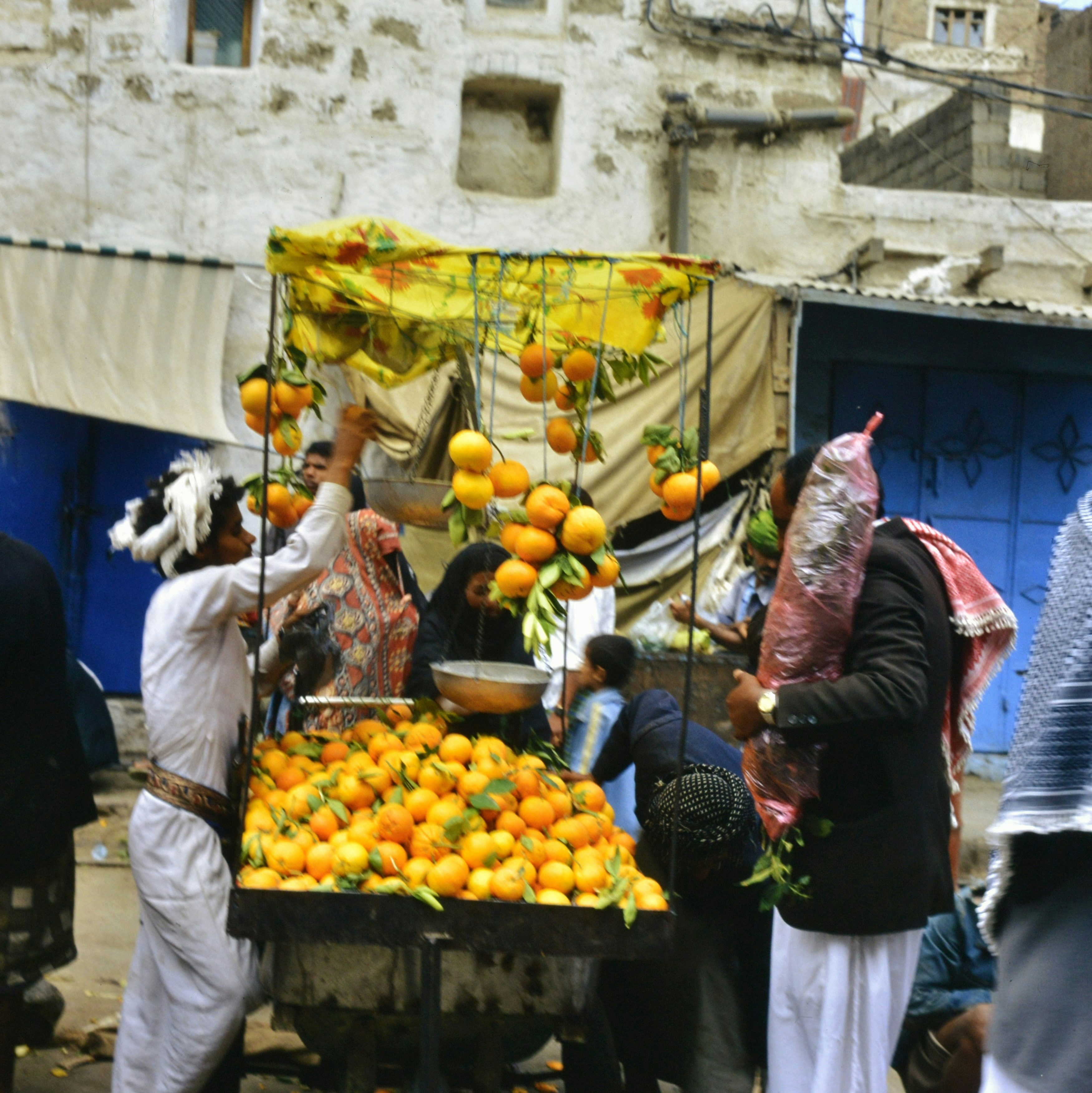 People buying oranges from a street vendor's stall.